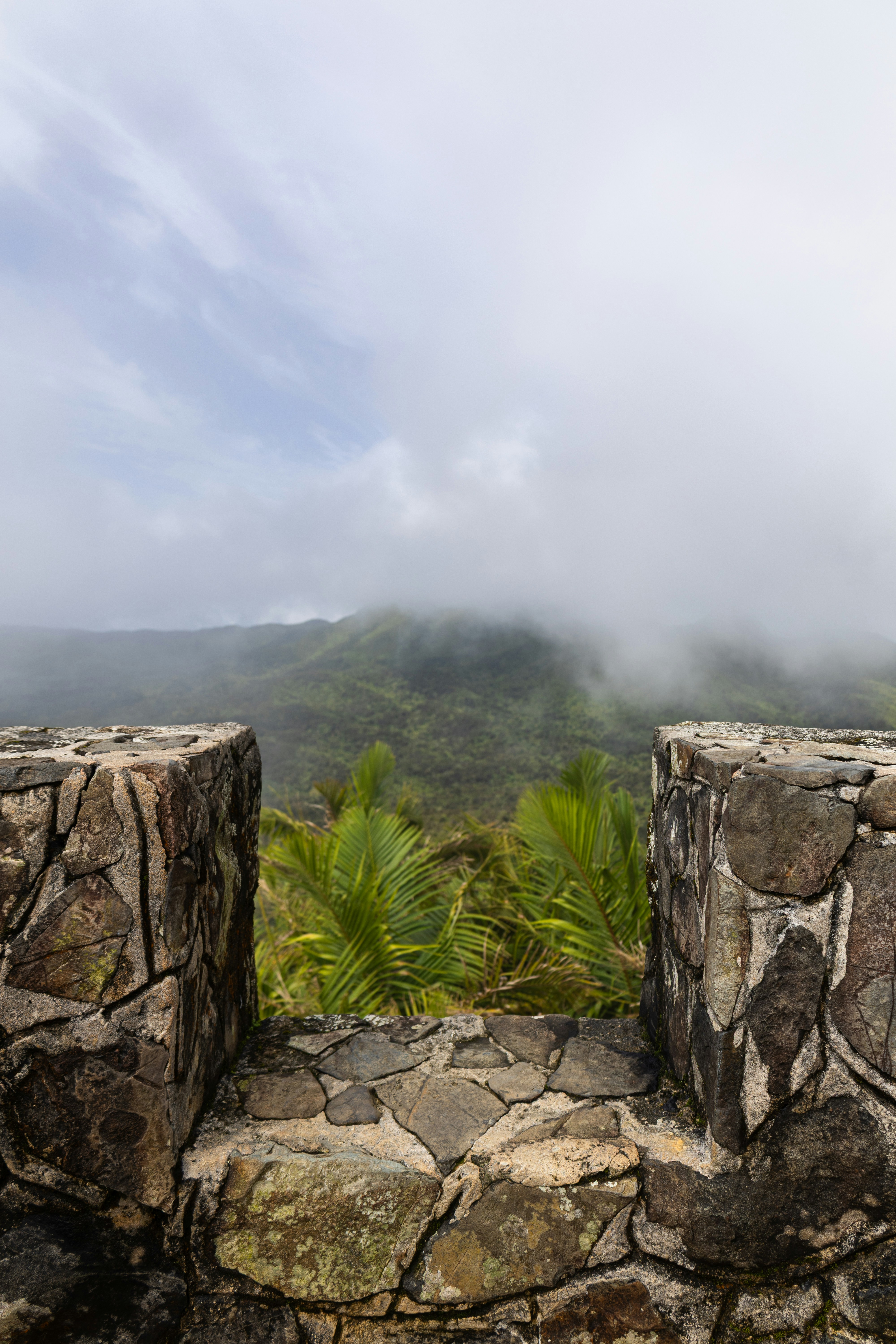Stone wall frames a misty mountain vista.
