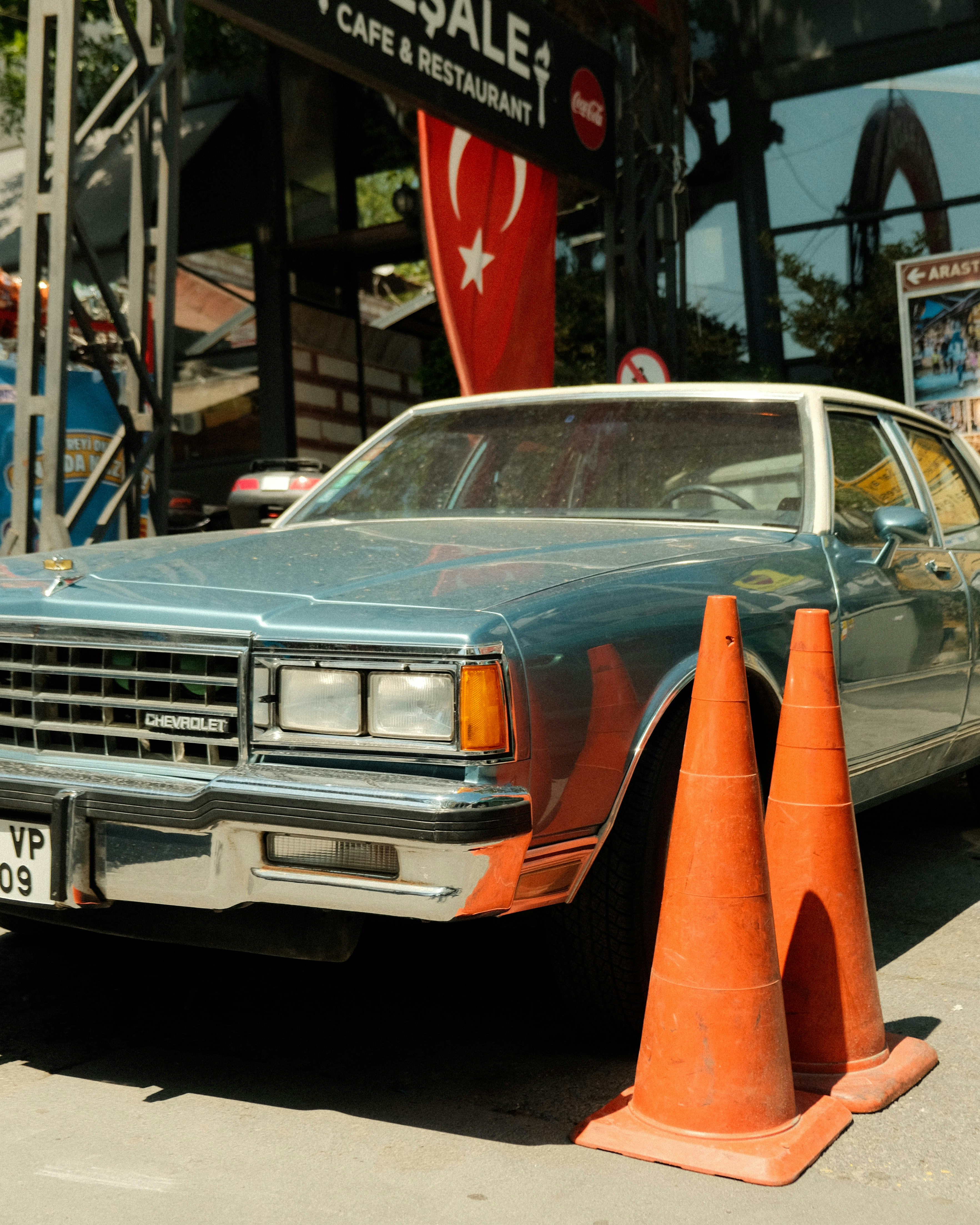 An old chevrolet car sits near orange cones