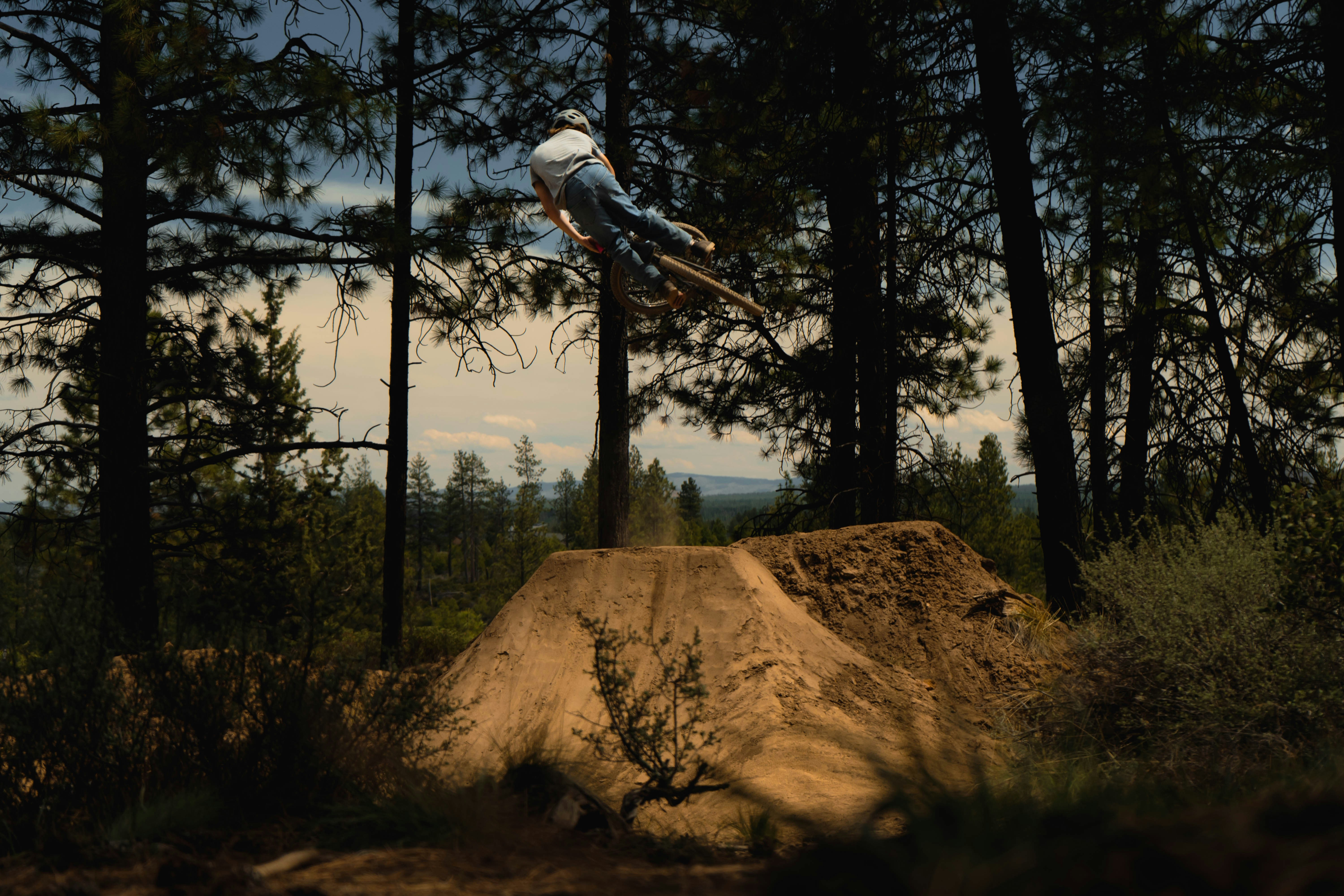 A biker jumps over a dirt mound.