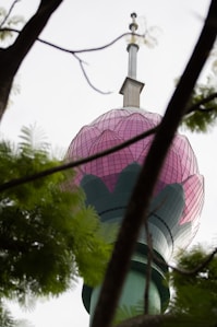 A pink and green tower is visible through trees.
