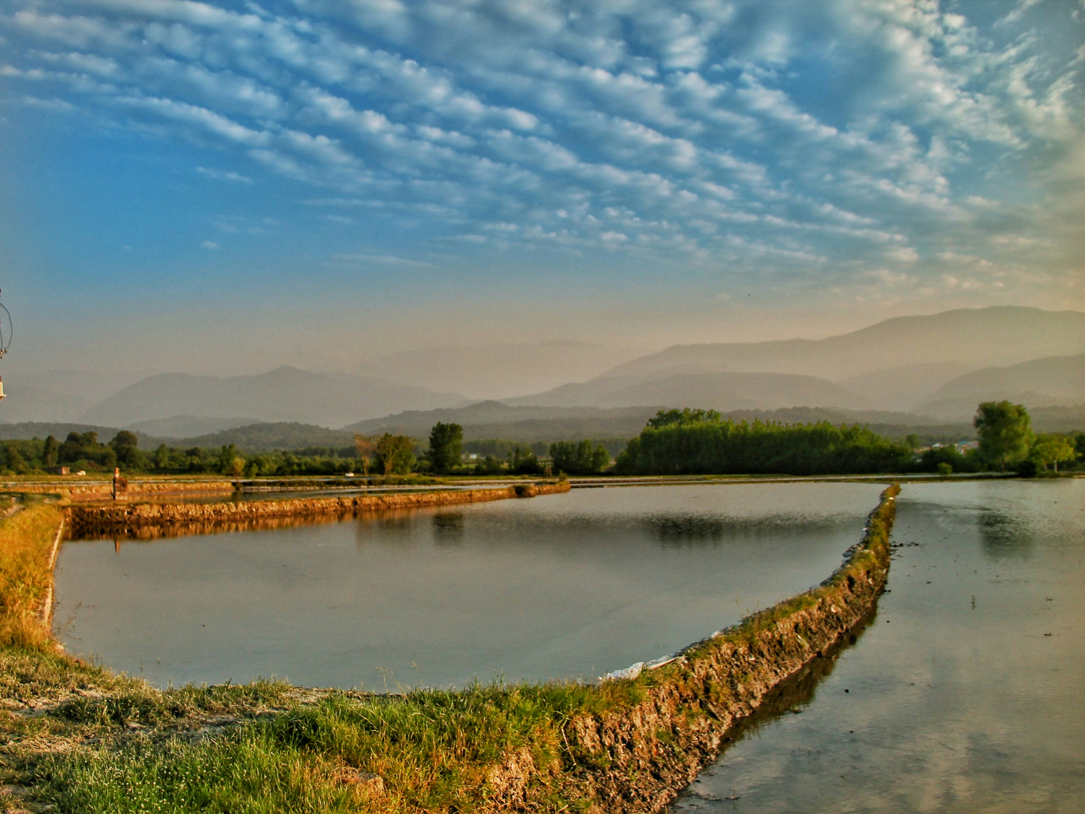 Reflective water and clouds reflect in a scenic landscape.