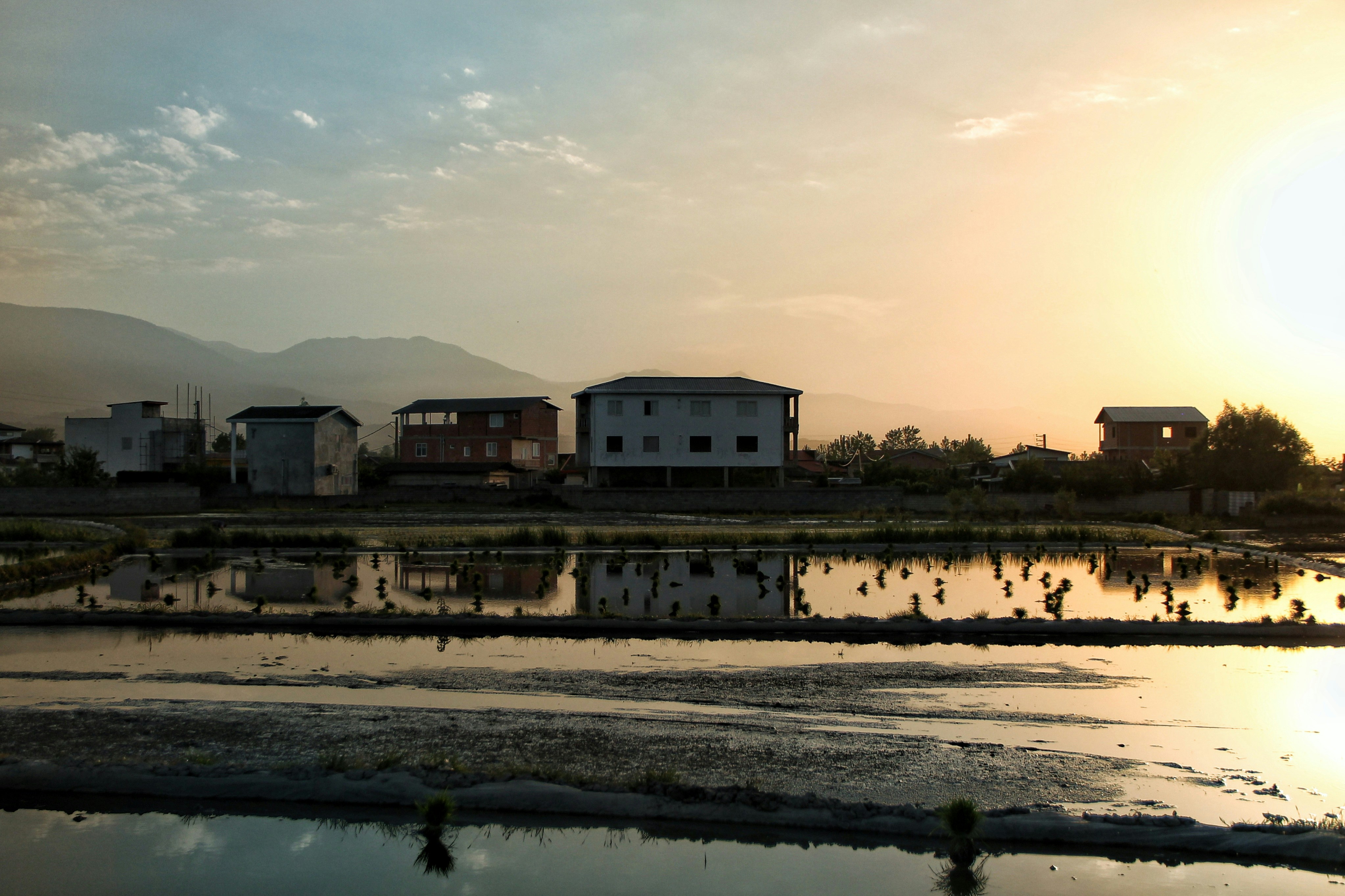 Houses reflect in the water during a scenic sunset.