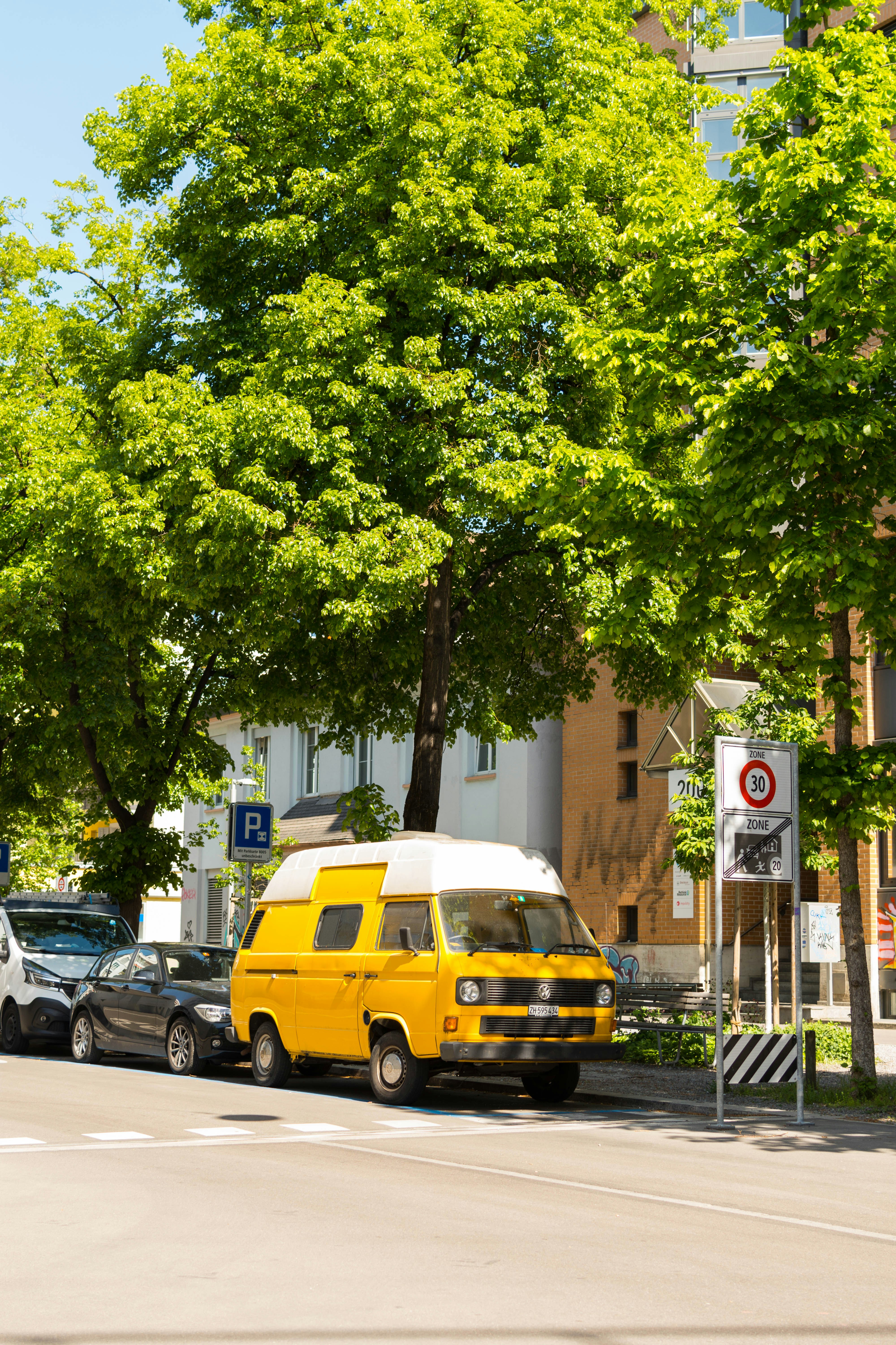 A yellow van parked on a sunny city street.
