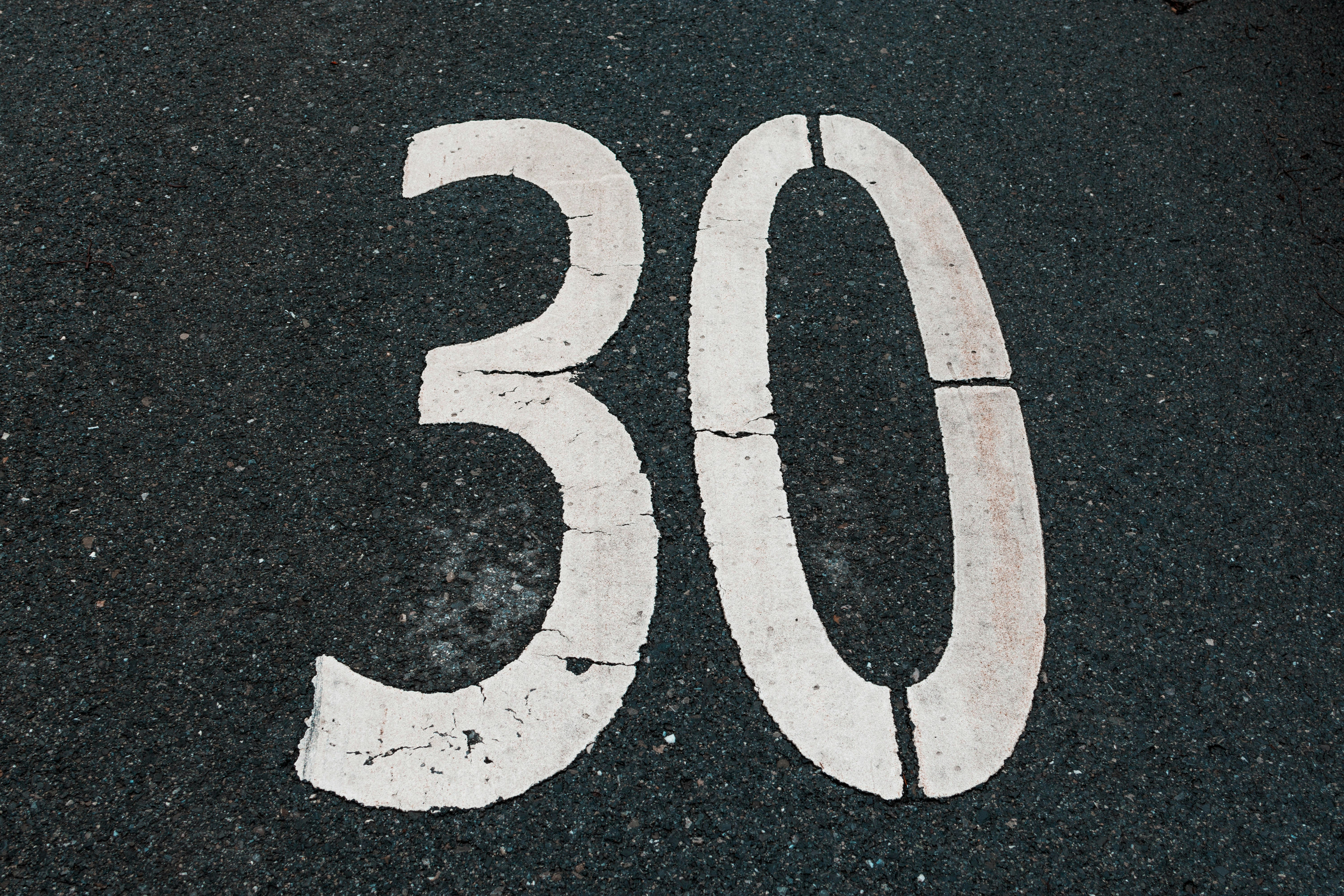 The number thirty is painted on asphalt.