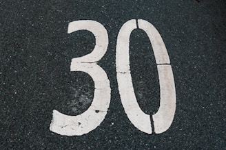 The number thirty is painted on asphalt.