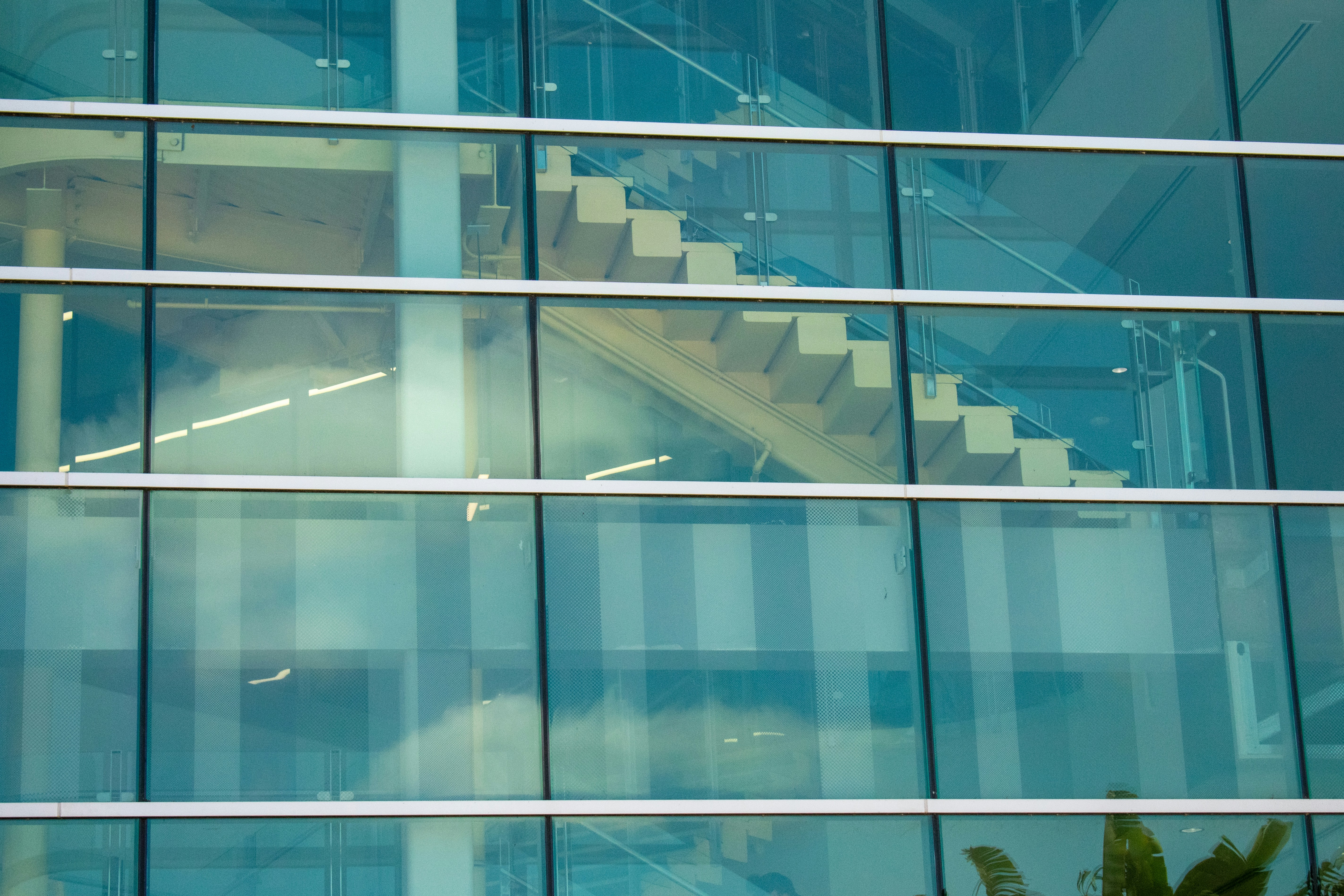A glass building shows staircase through windows.