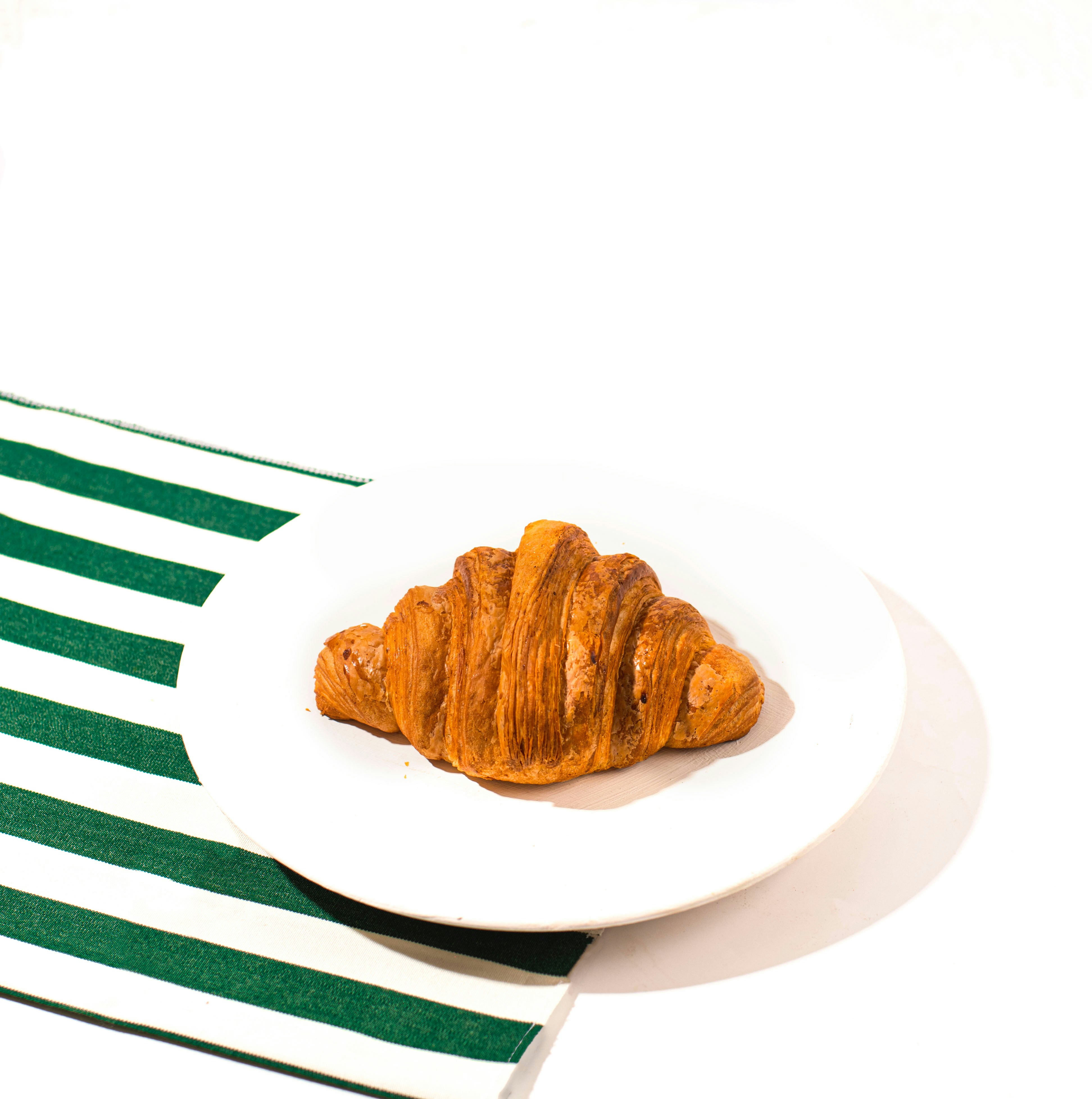 A delicious croissant rests on a white plate.