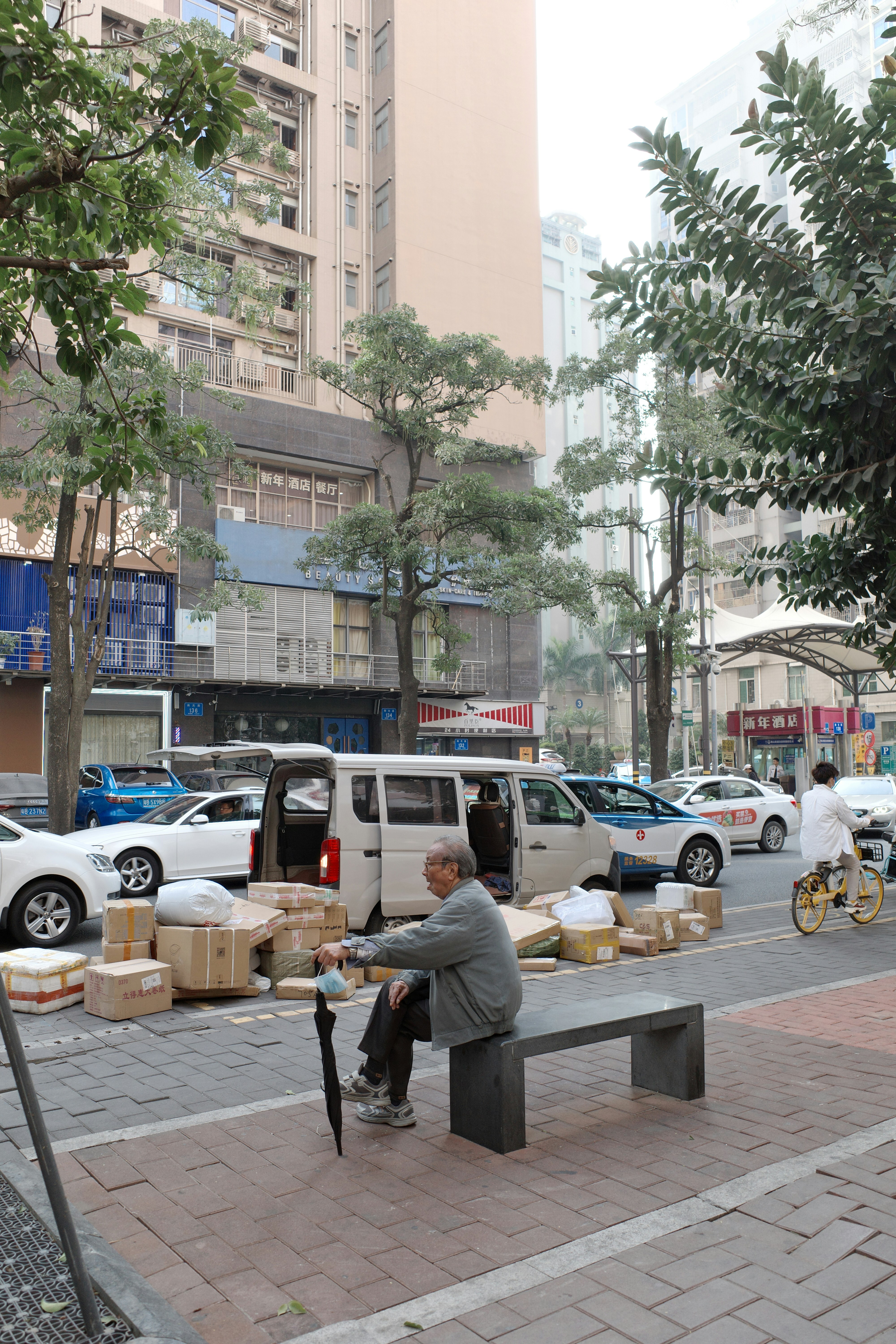 A man sits near boxes on a city street.