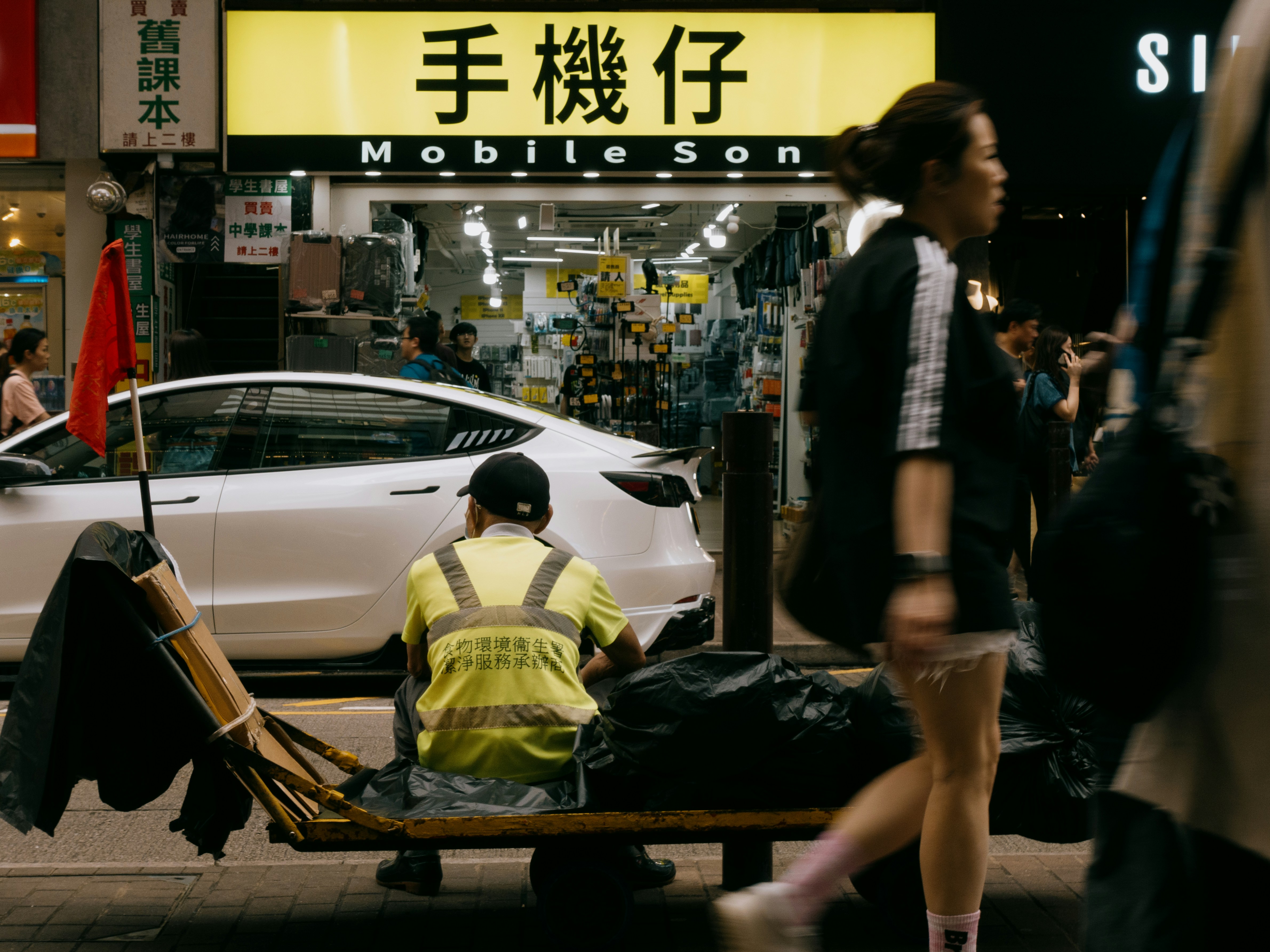 A street scene with people and a mobile phone shop.