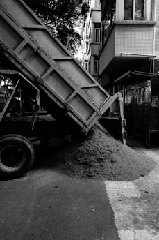 A dump truck unloads sand on the road.