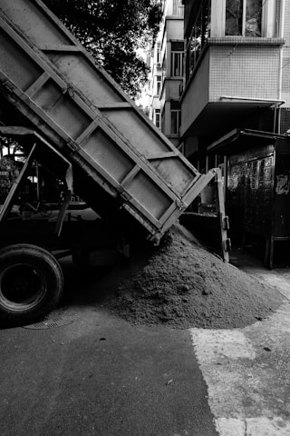 A dump truck unloads sand on the road.