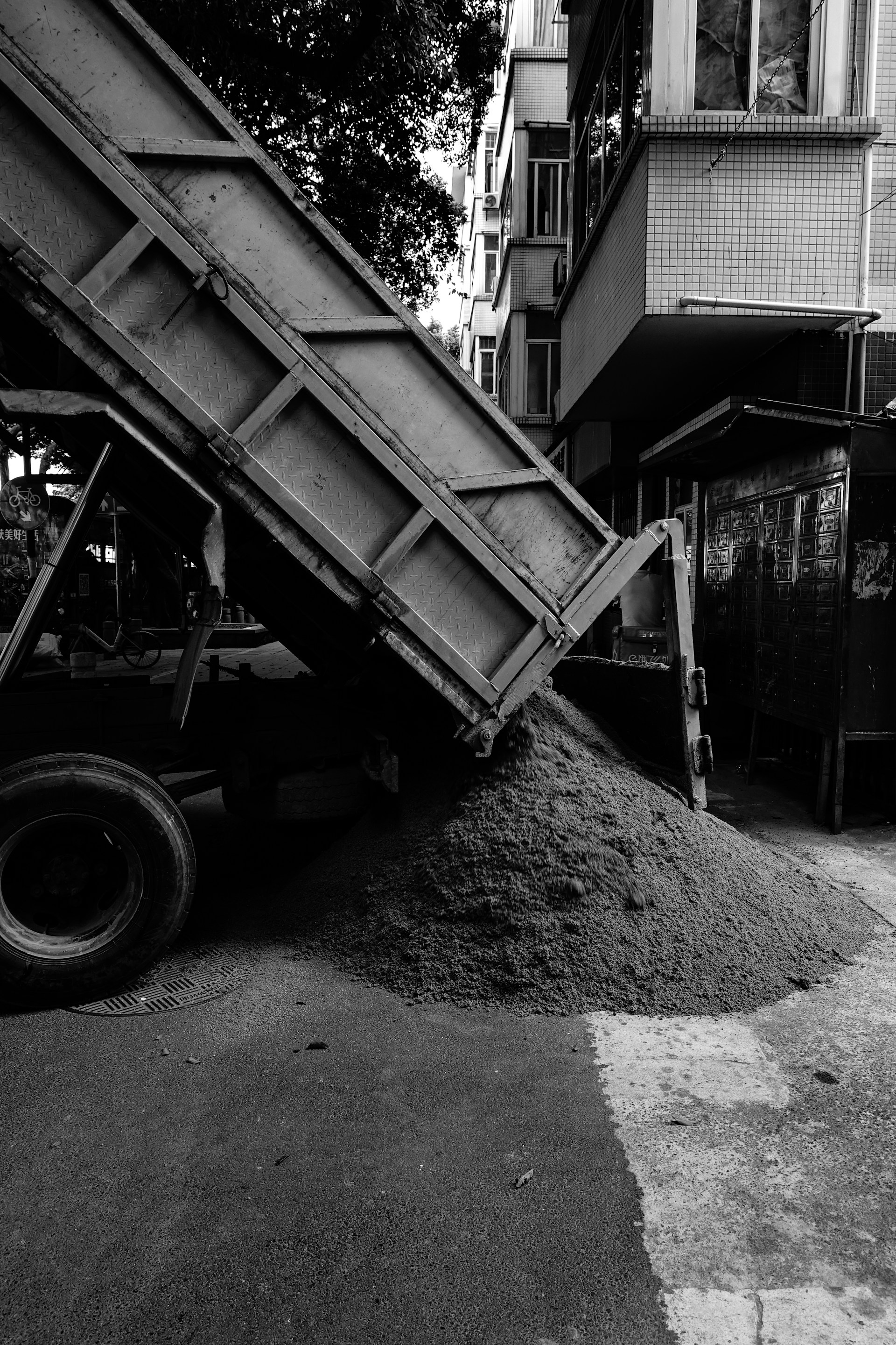 A dump truck unloads sand on the road.