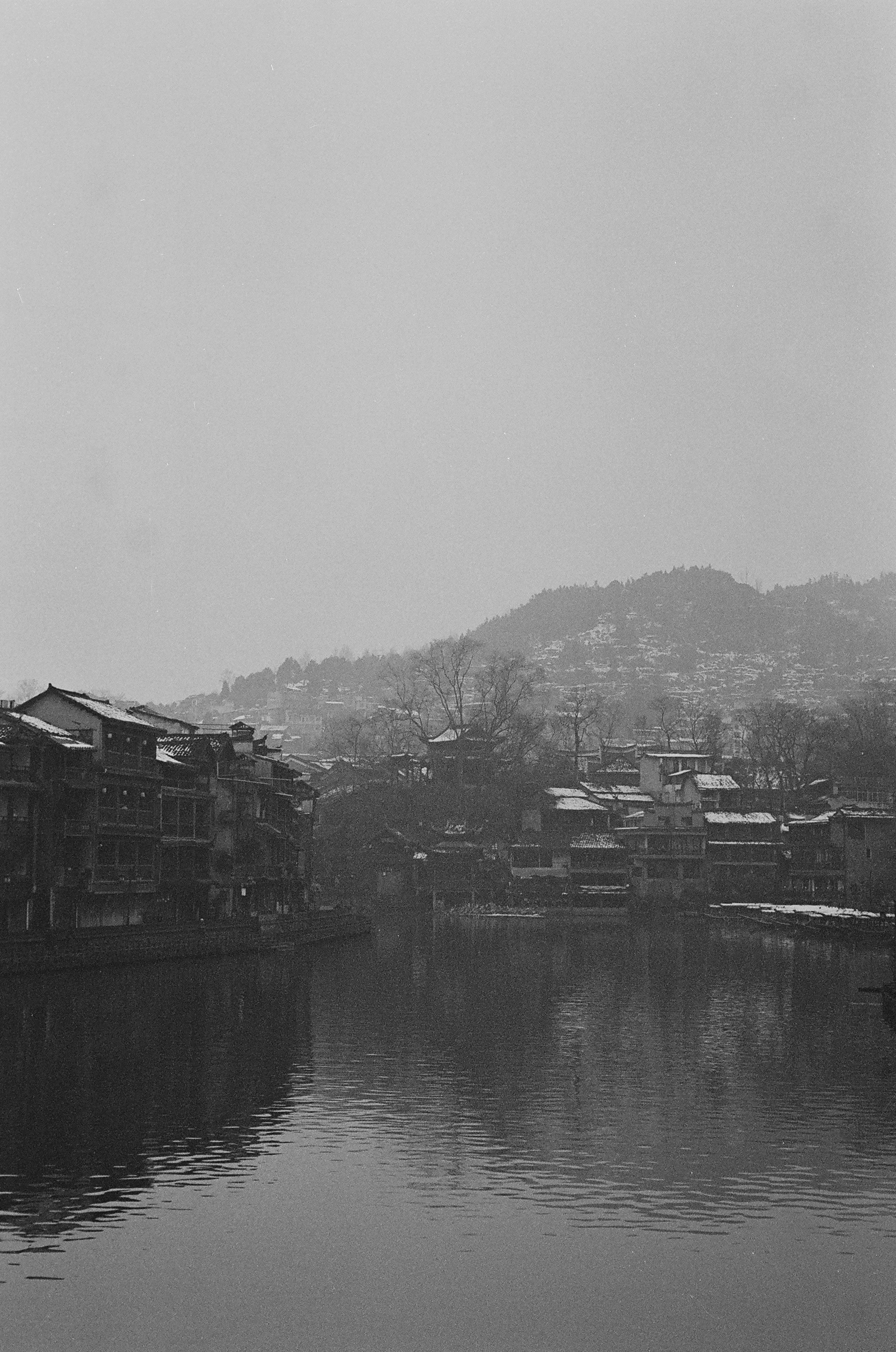 Houses line the river in this grayscale shot.