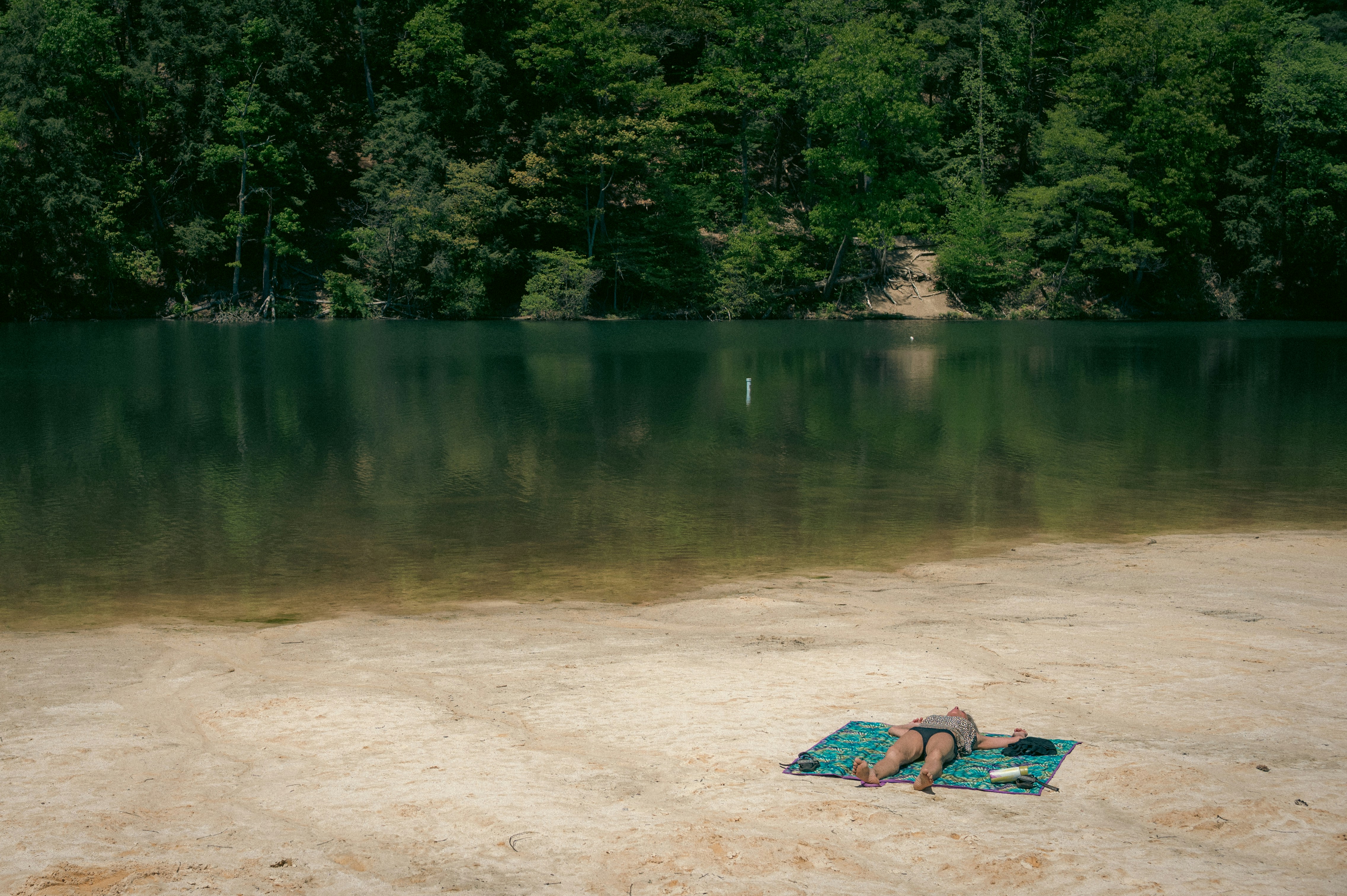 Seseorang bersantai di tepi danau pada hari yang cerah.