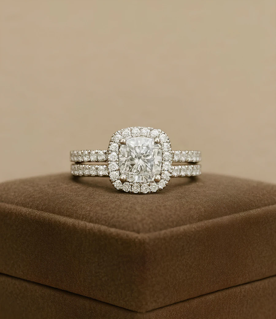 A cushion halo engagement ring with a matching band on brown velvet