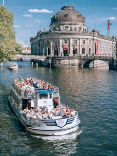 A sightseeing boat sails in front of a building.