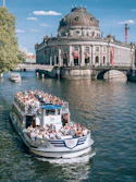 A sightseeing boat sails in front of a building.
