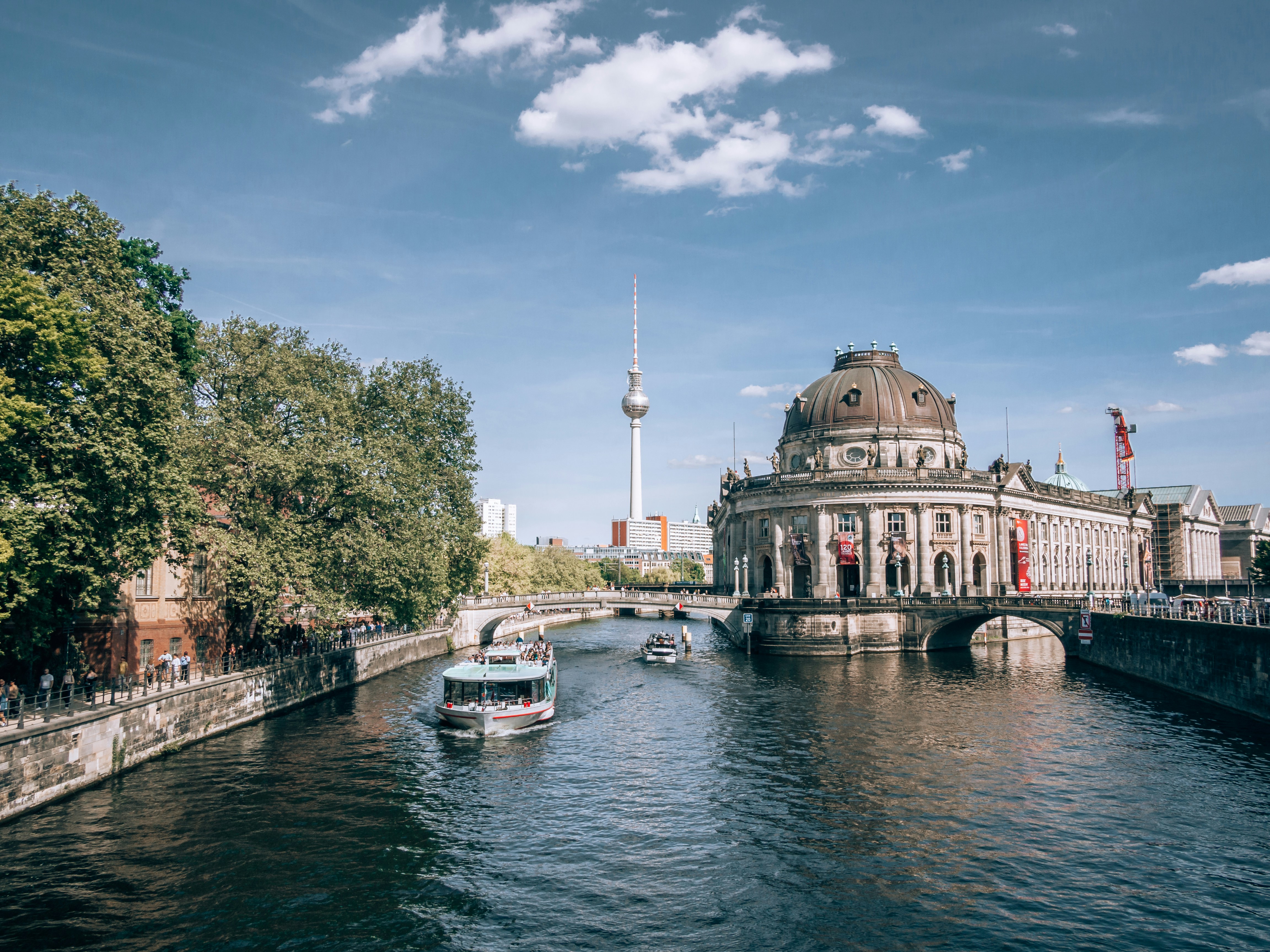 Berlin's cityscape with river and iconic architecture.