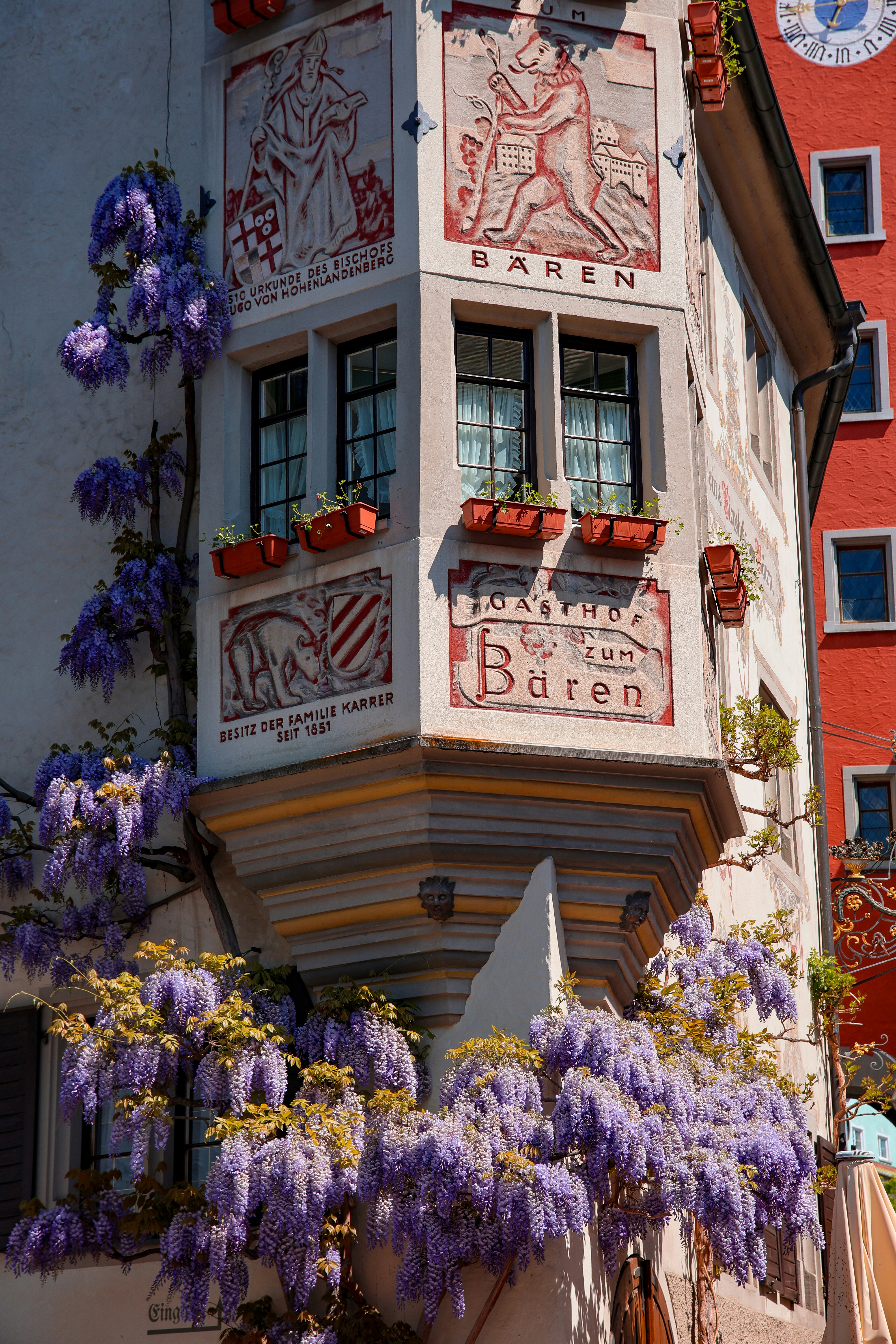 Beautiful building corner adorned with wisteria blooms.