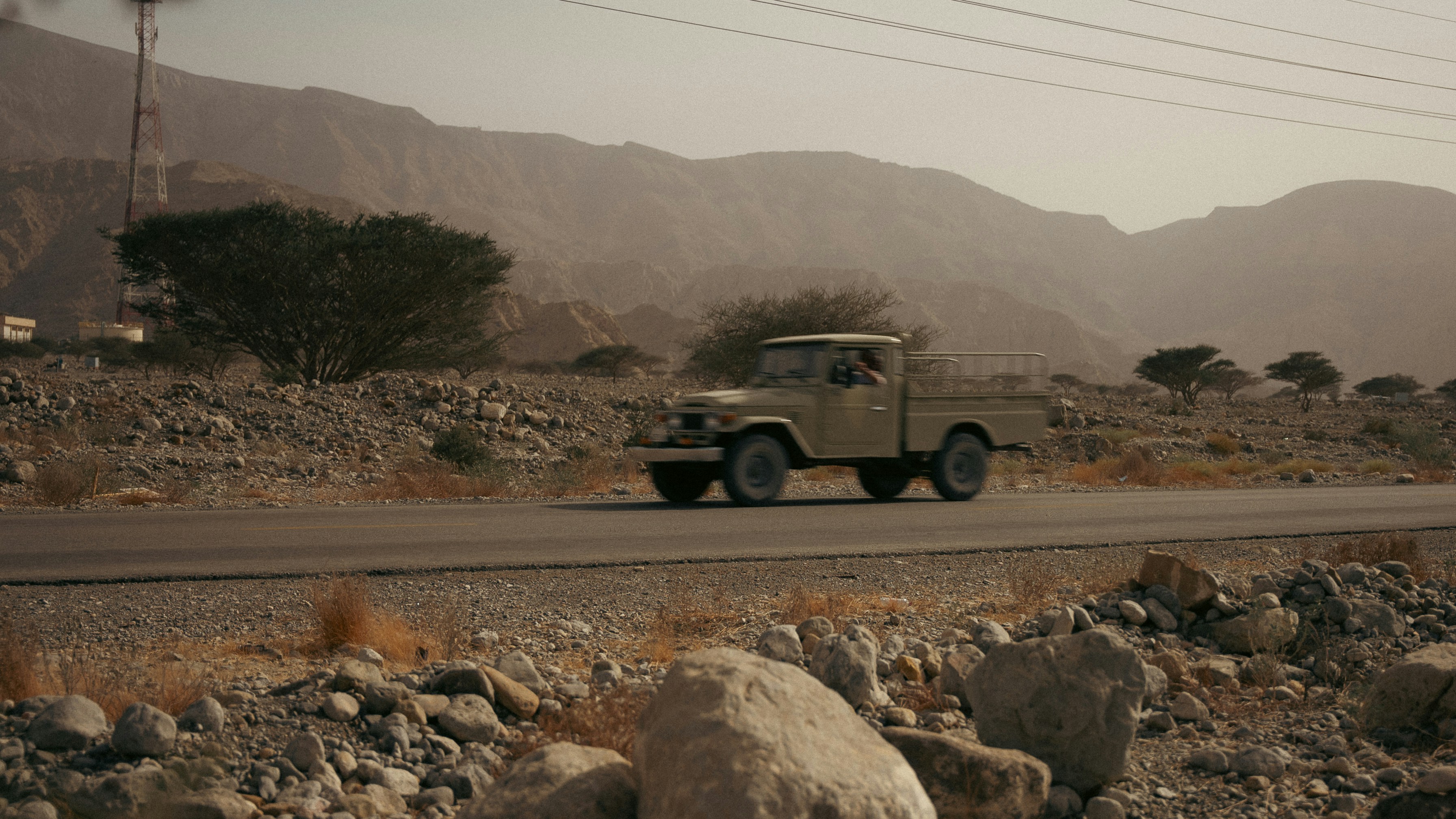 A vehicle drives on a road in a mountainous landscape.