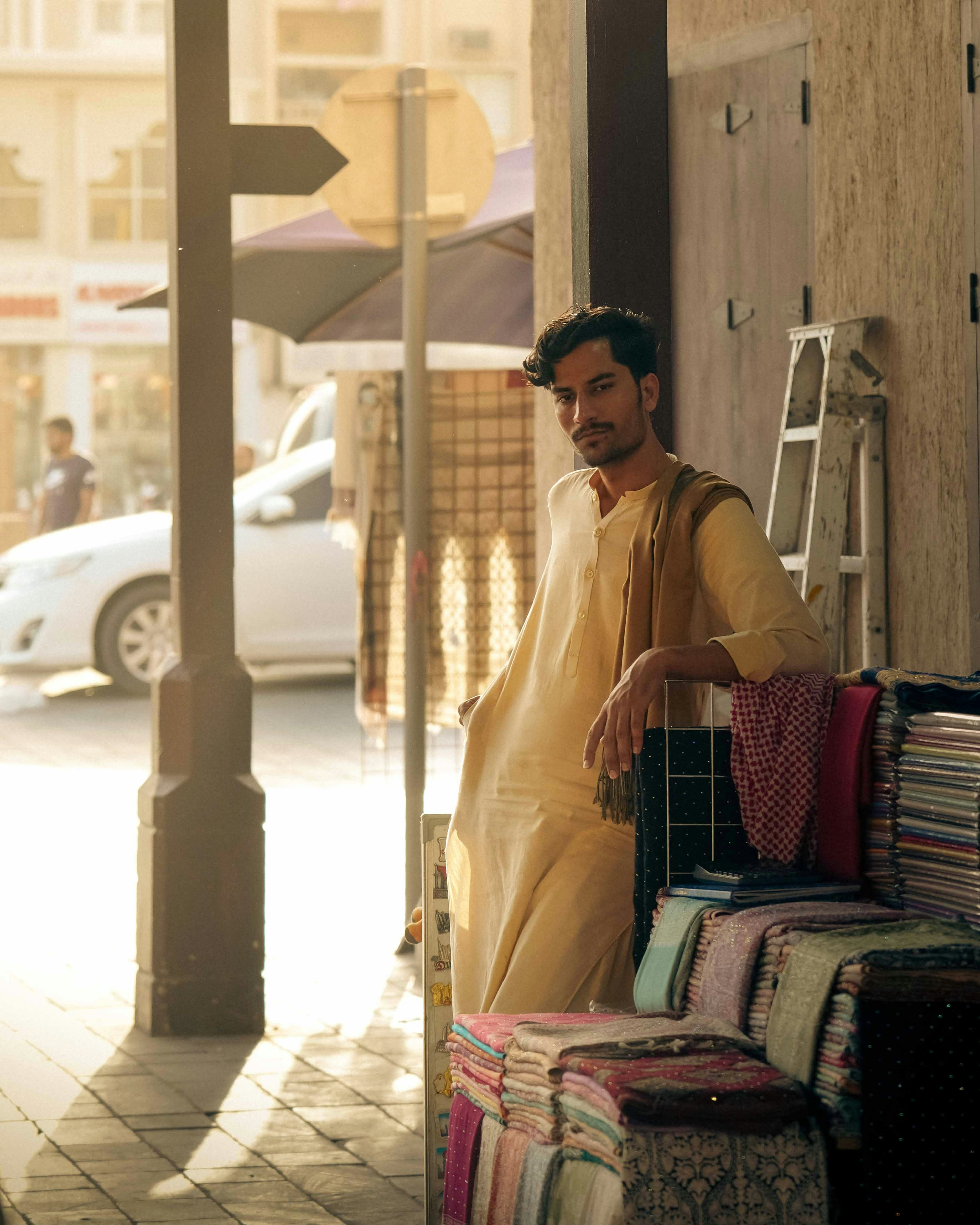 A man smiles while standing beside goods.