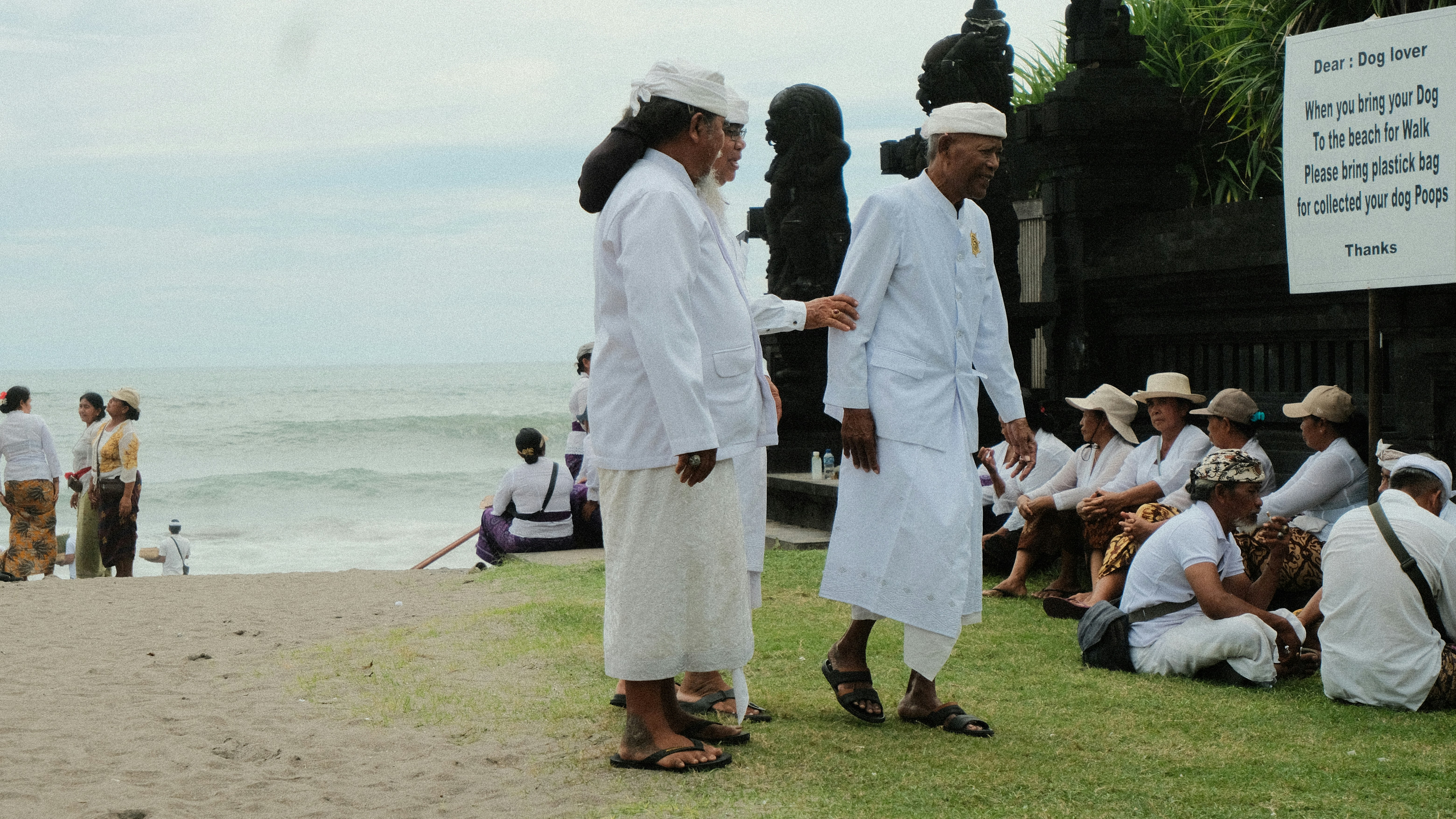 Orang-orang berpakaian putih di sebuah upacara di pantai.