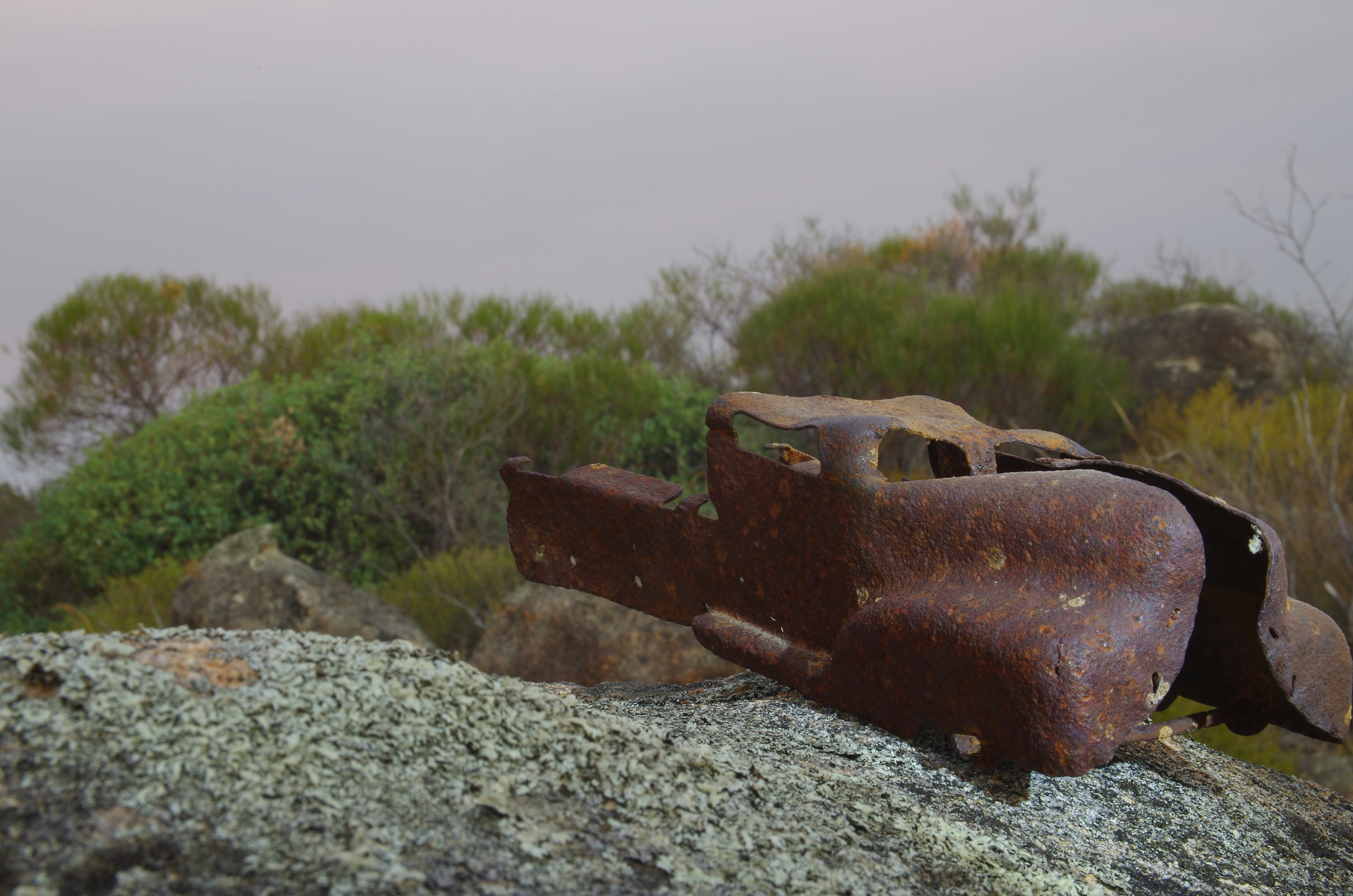 Rusty metal rests on a weathered rock.