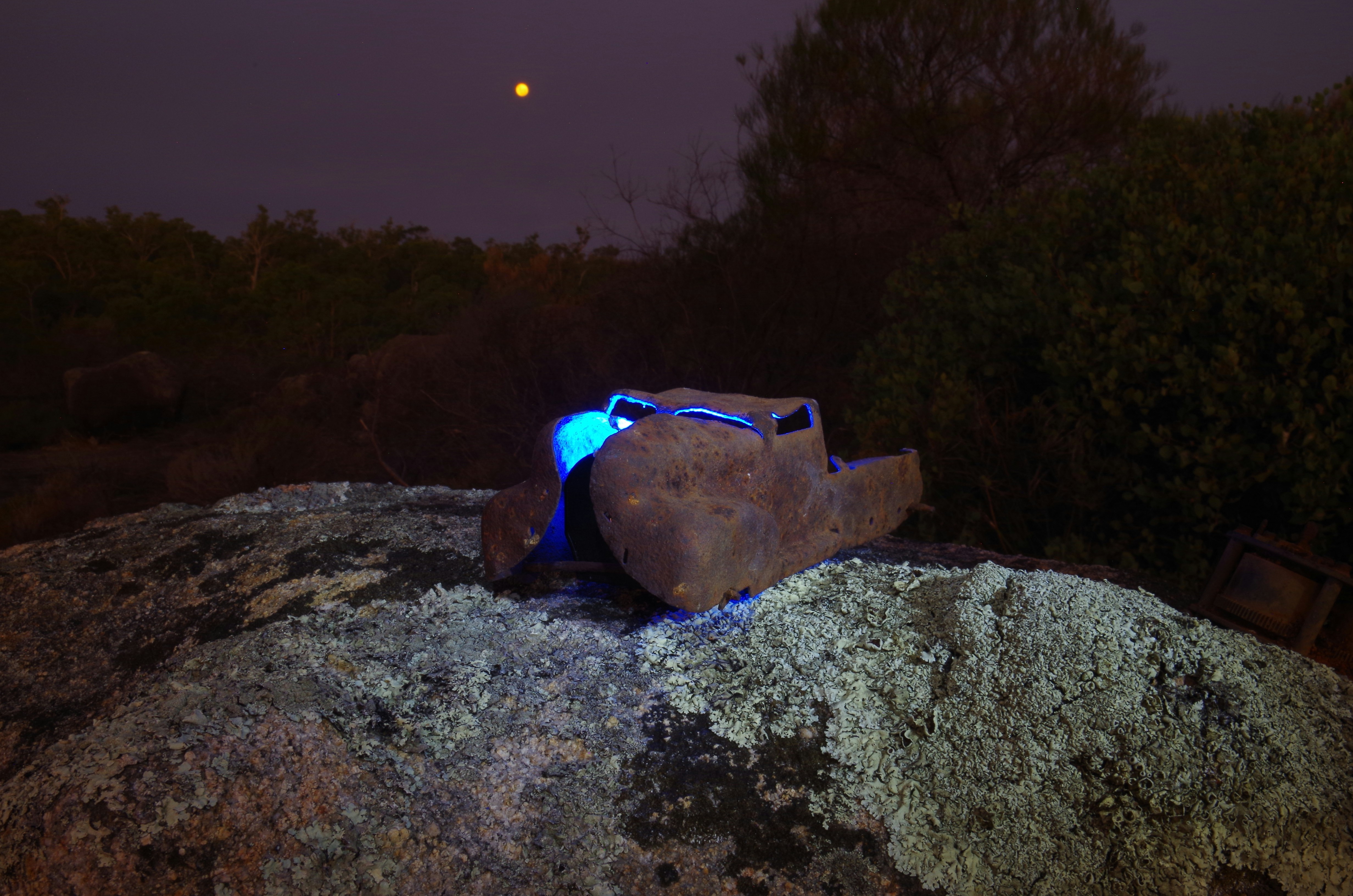 Glowing object sits atop a rocky surface at night.