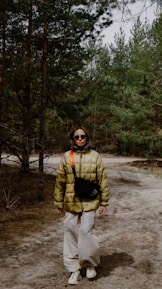 Person stands in forest wearing a puffy jacket.