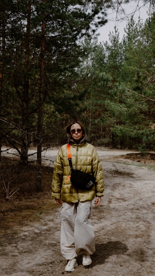 Person stands in forest wearing a puffy jacket.