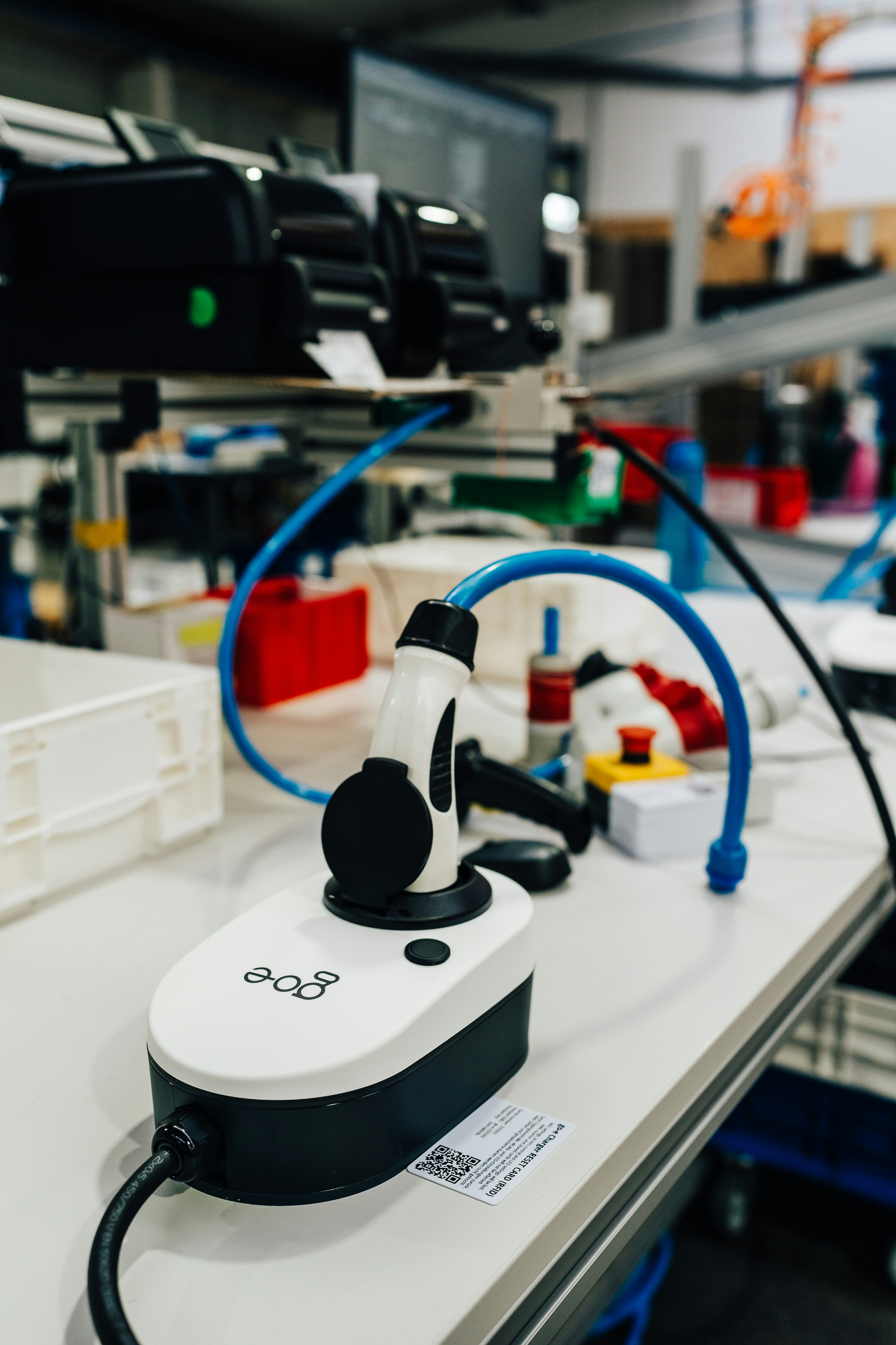 An electric vehicle charger sits on a workbench.