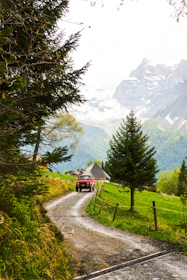 A red car drives on a mountain road.
