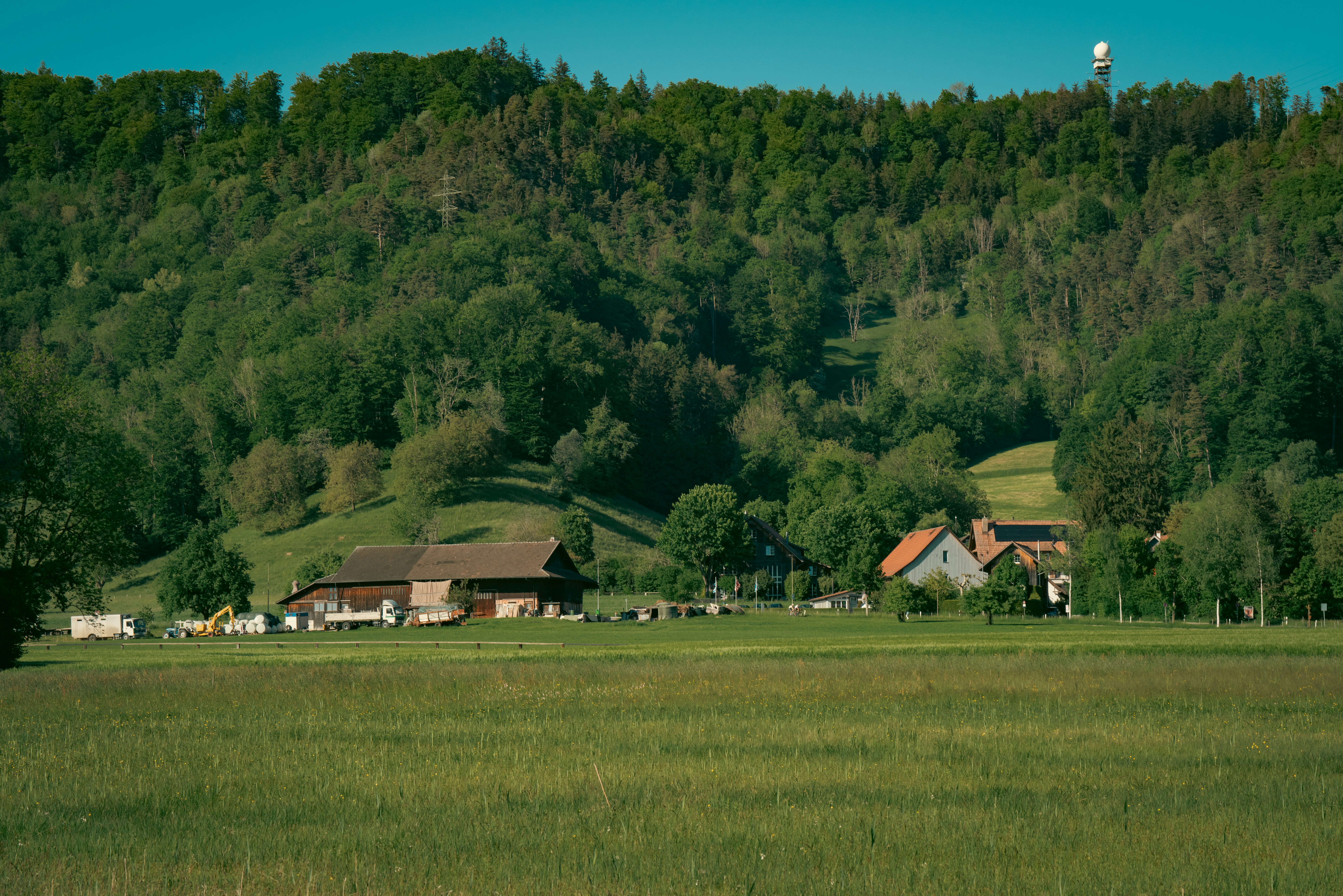 A farm sits in a green, sunny field.