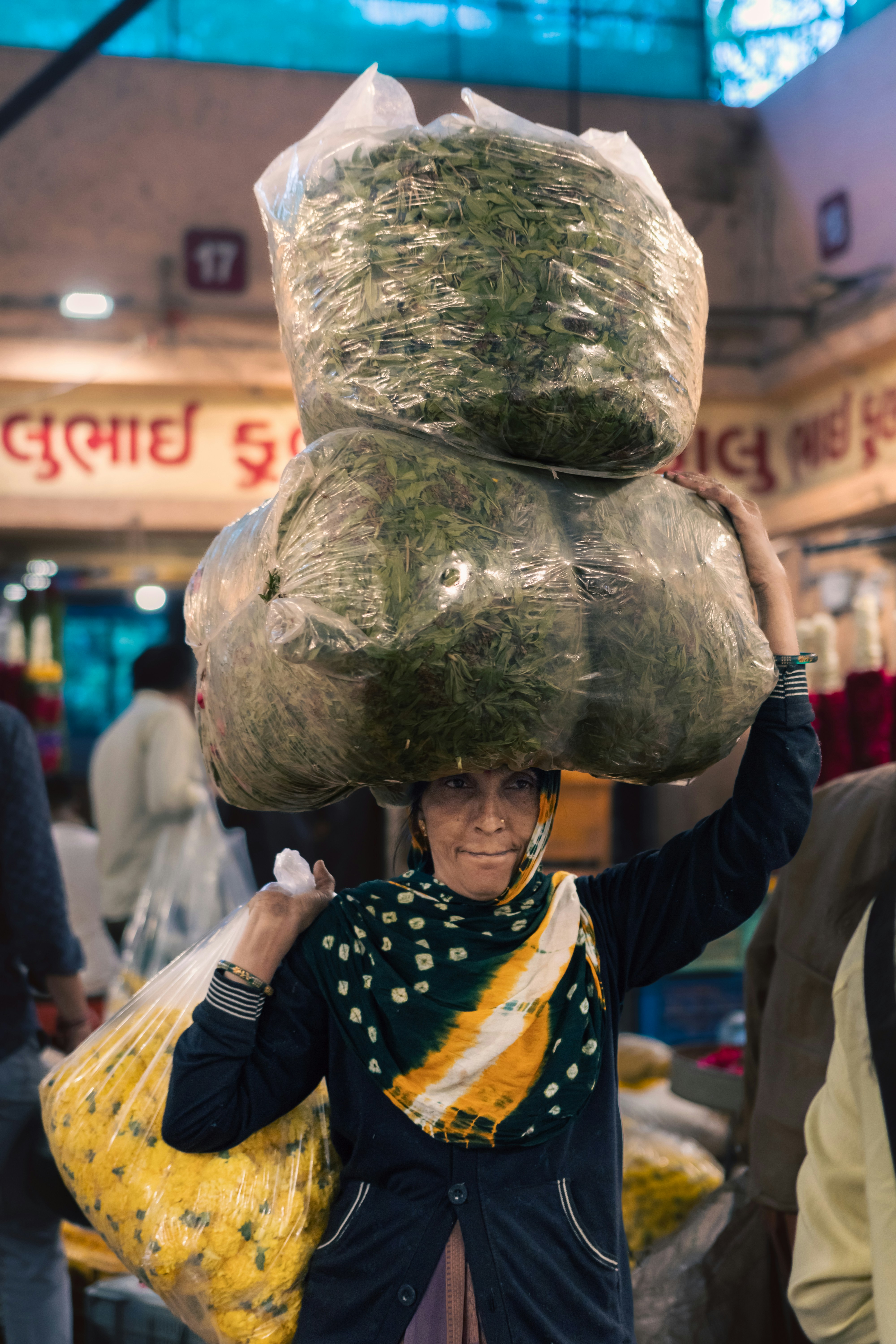 Woman balances sacks of flowers on her head.