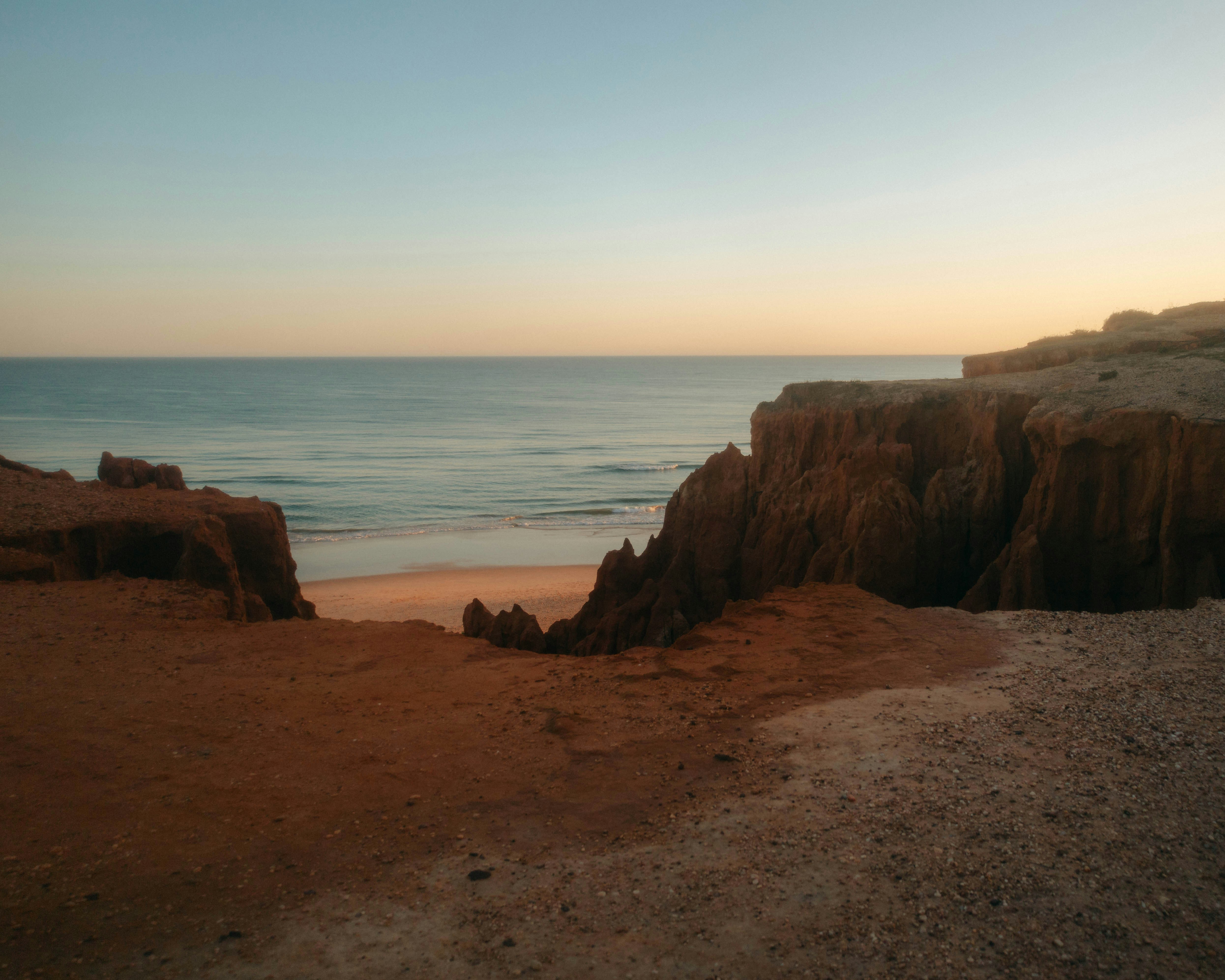 Coastal cliffs overlook the ocean during sunset.