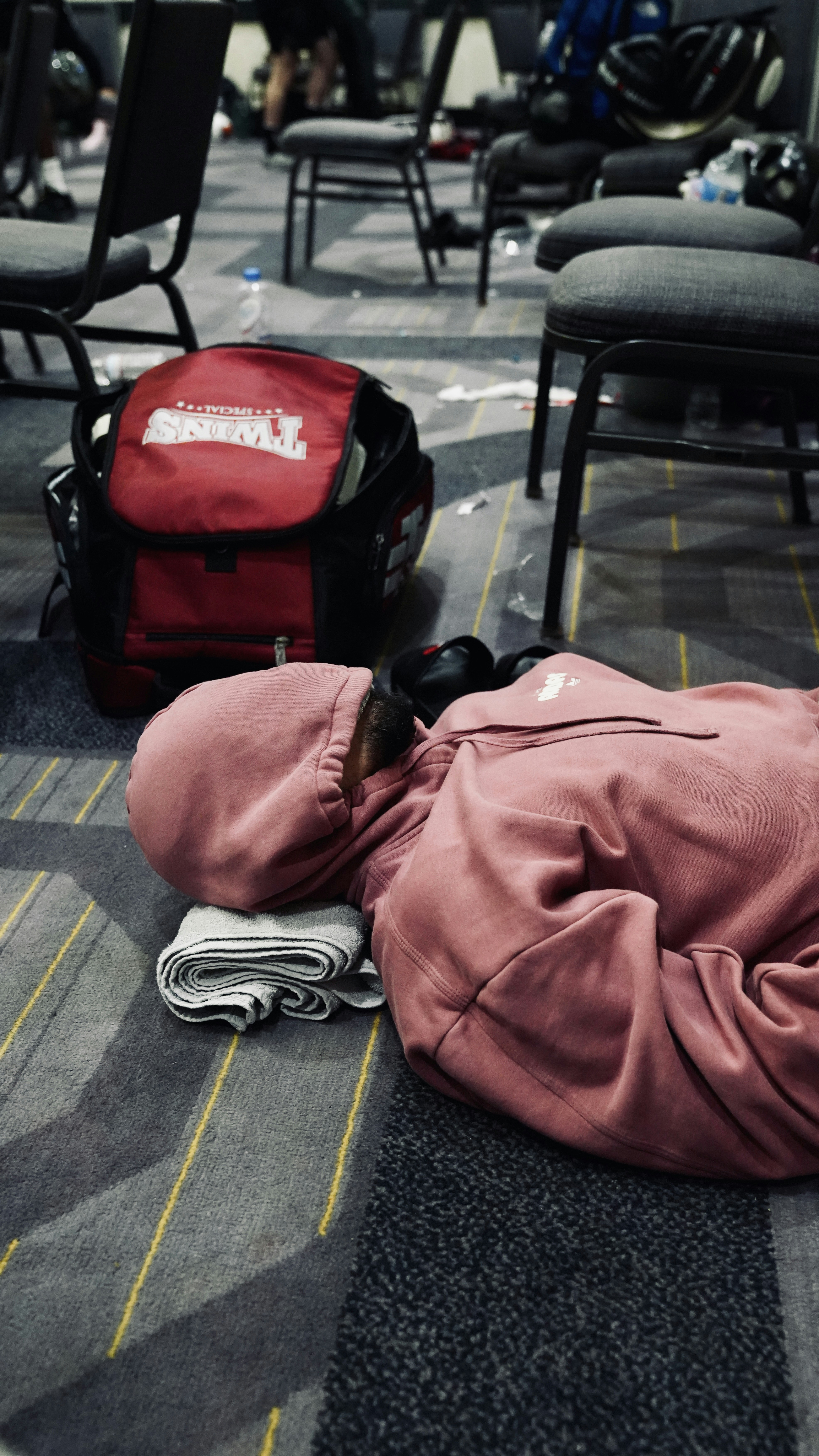 Person sleeping on the floor near a backpack.