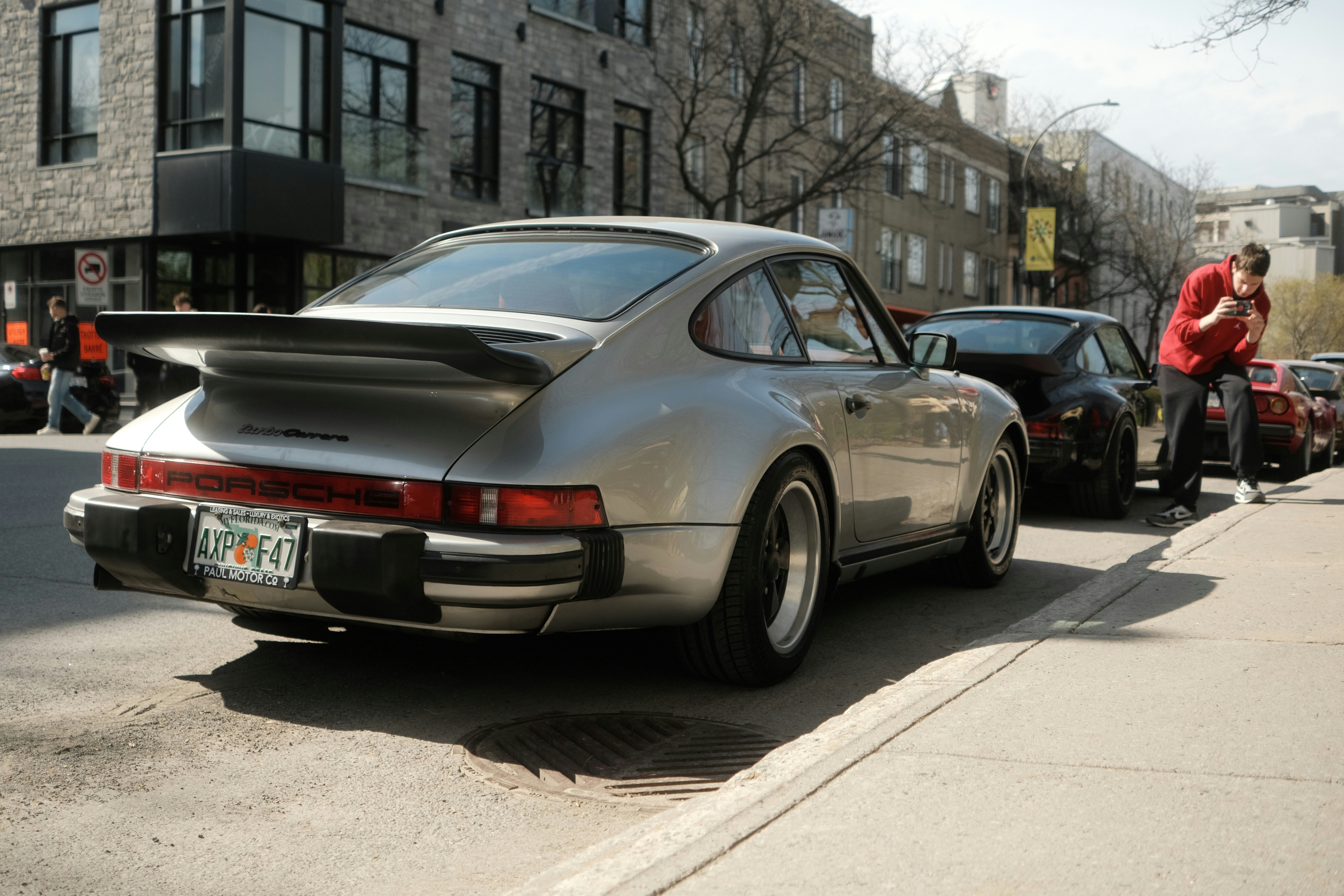A silver porsche parked on the street.