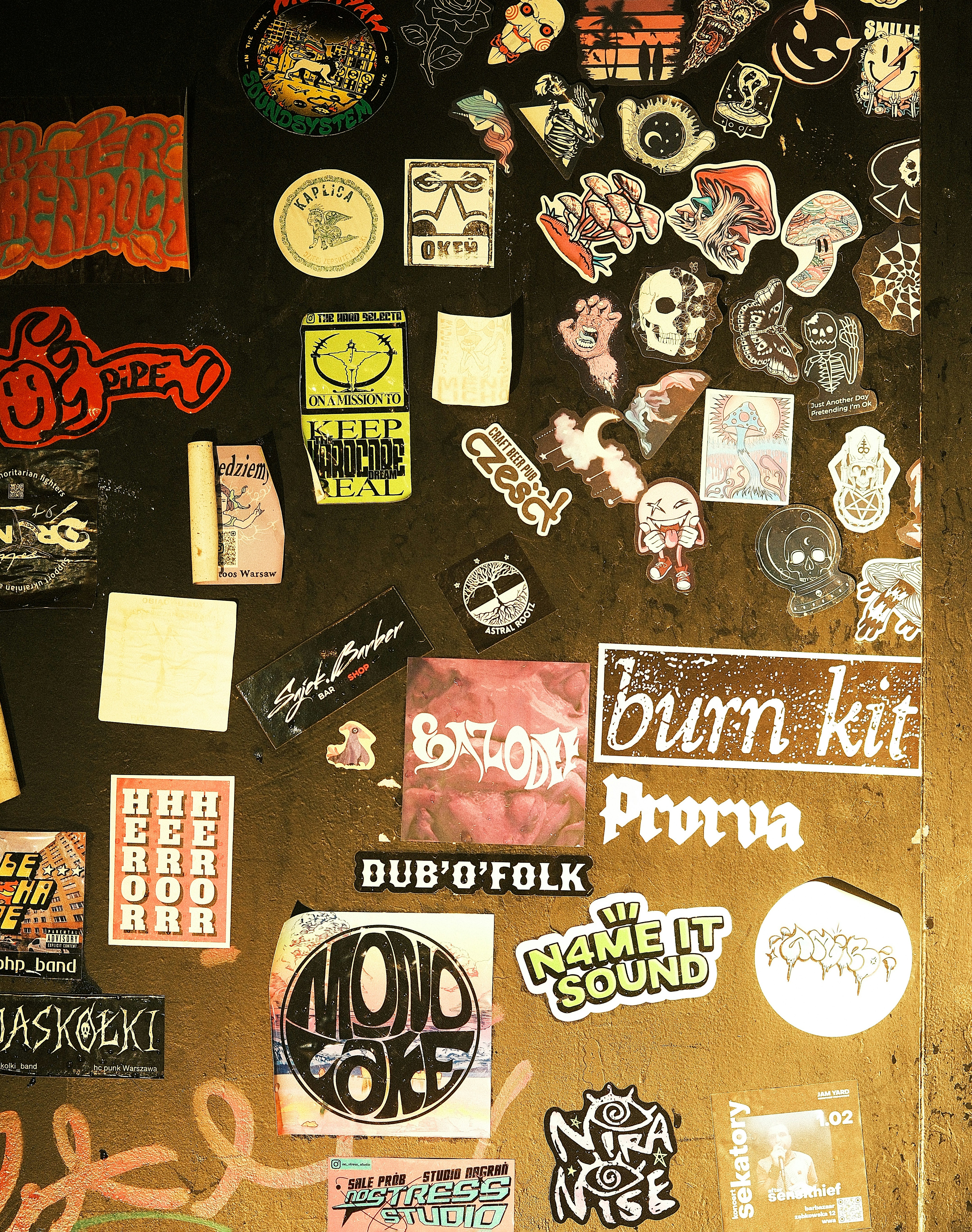 Many colorful stickers cover a dark, textured surface.