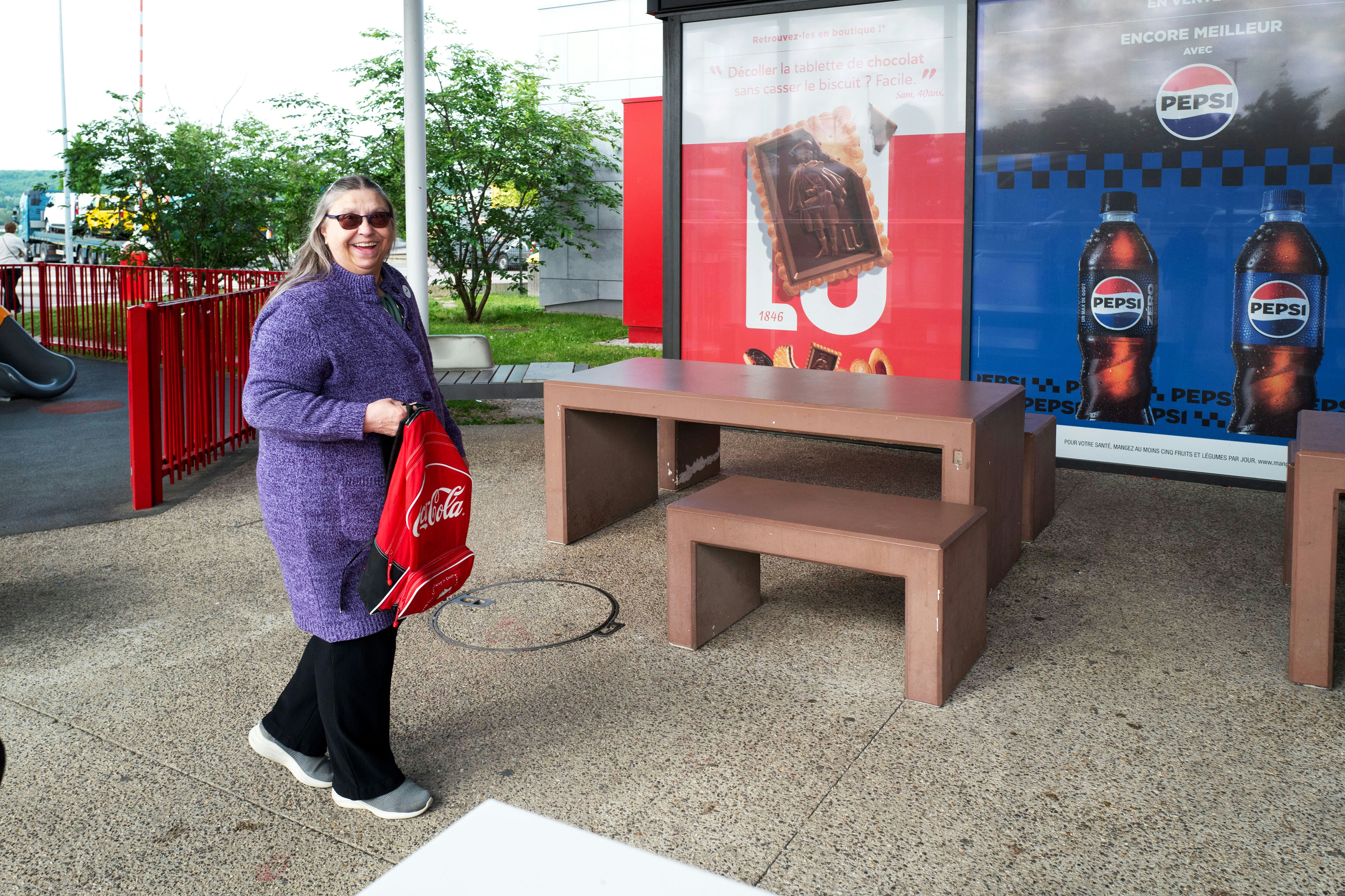 Una mujer posa junto a anuncios de Pepsi.