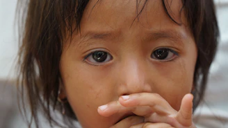 A young girl is looking at the viewer, sad.