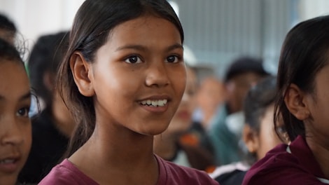 A young girl smiles among others.