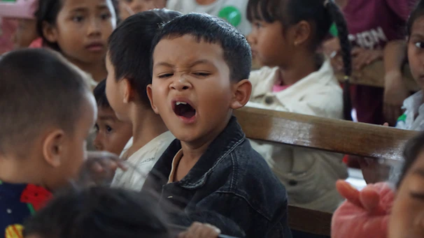 A young boy yawns amongst many others.
