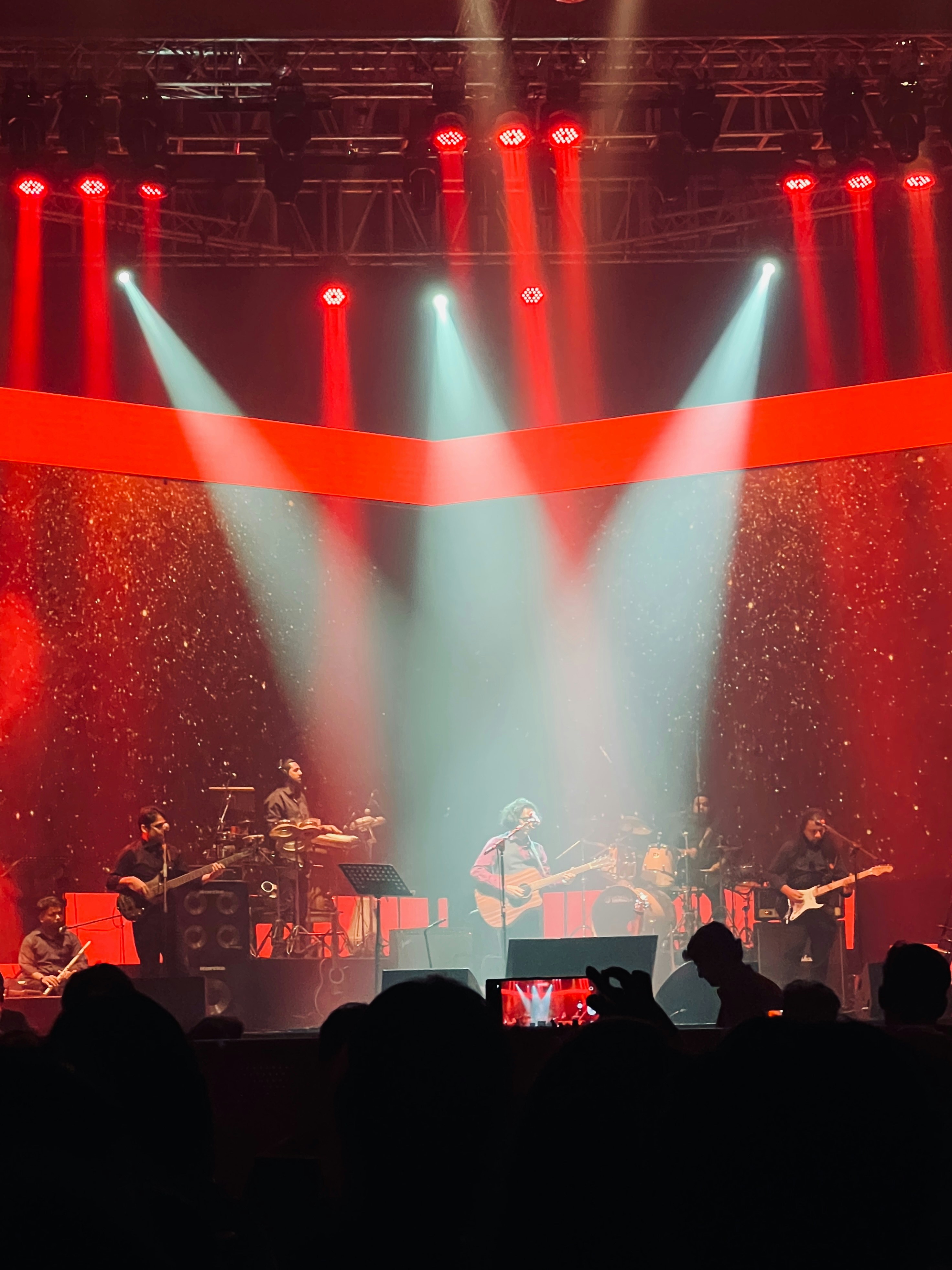 A band performs on a stage with bright lights.