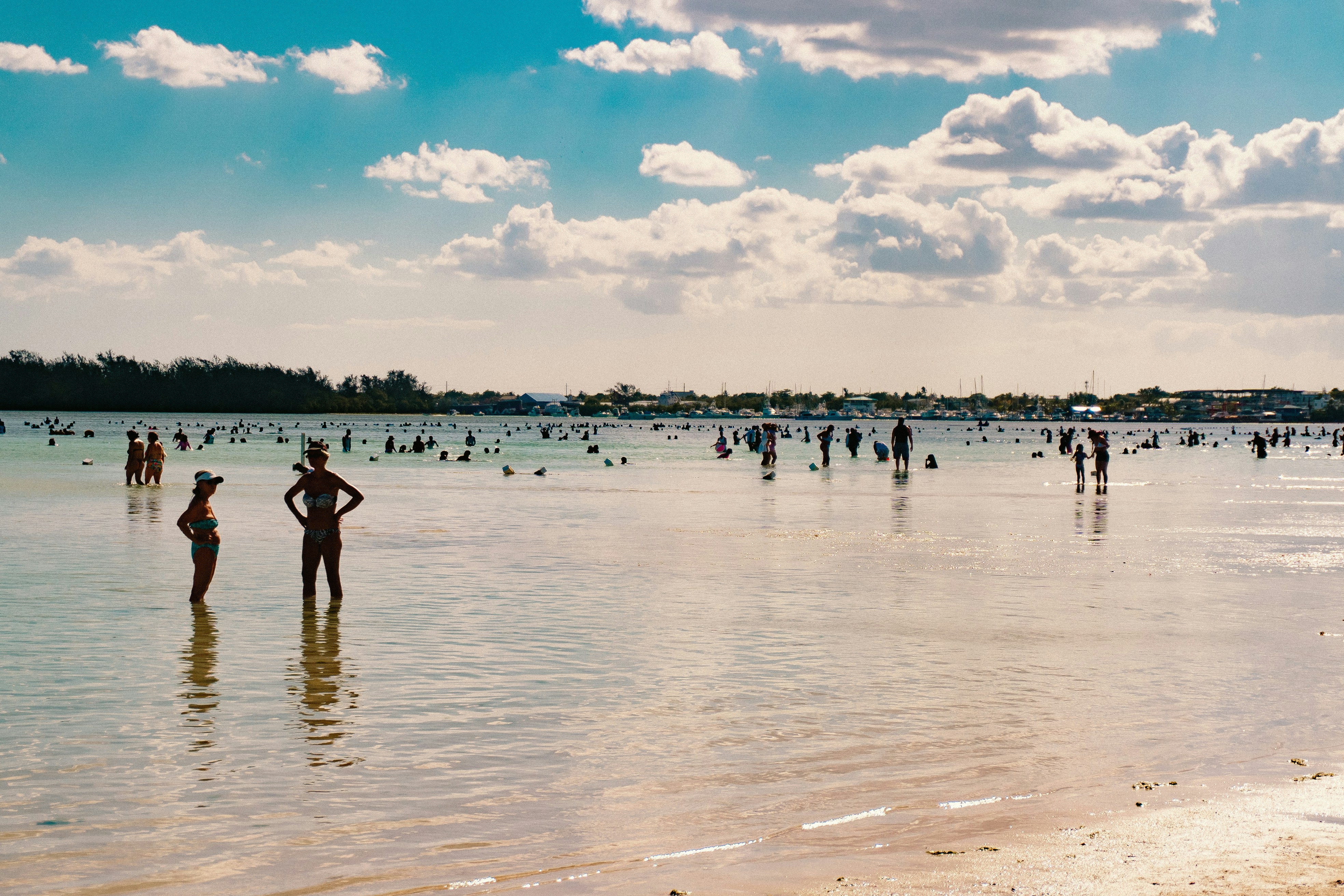 People swim and play in the shallow, clear water.