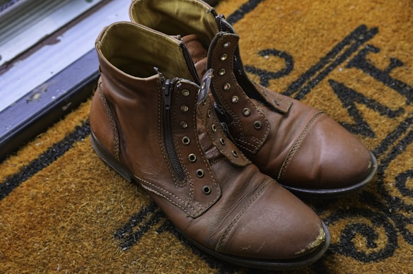 Brown boots rest on a welcoming door mat.