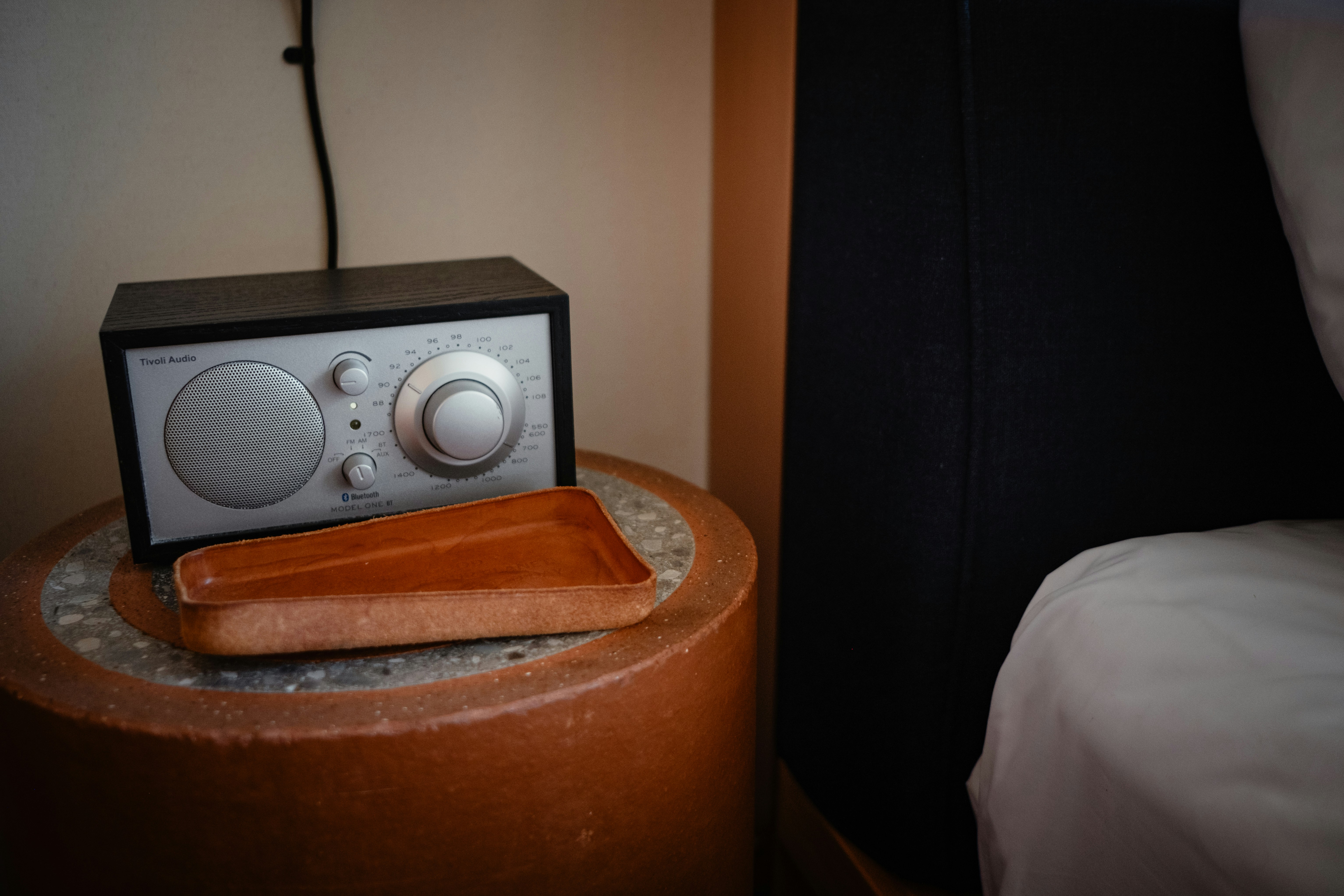 A radio, tray, and nightstand beside the bed.