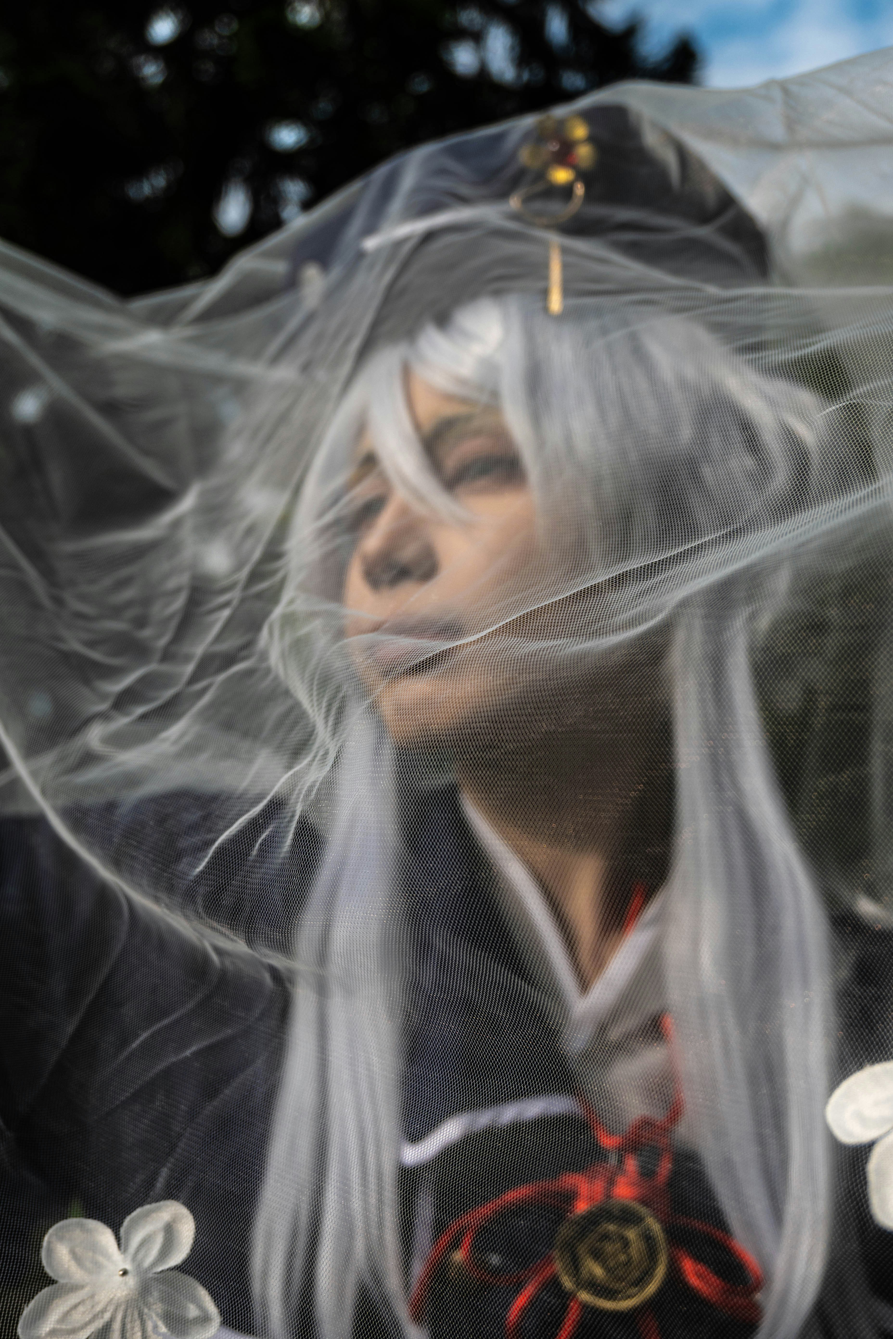 Cosplayer dengan wig putih dan kerudung dalam kostum.