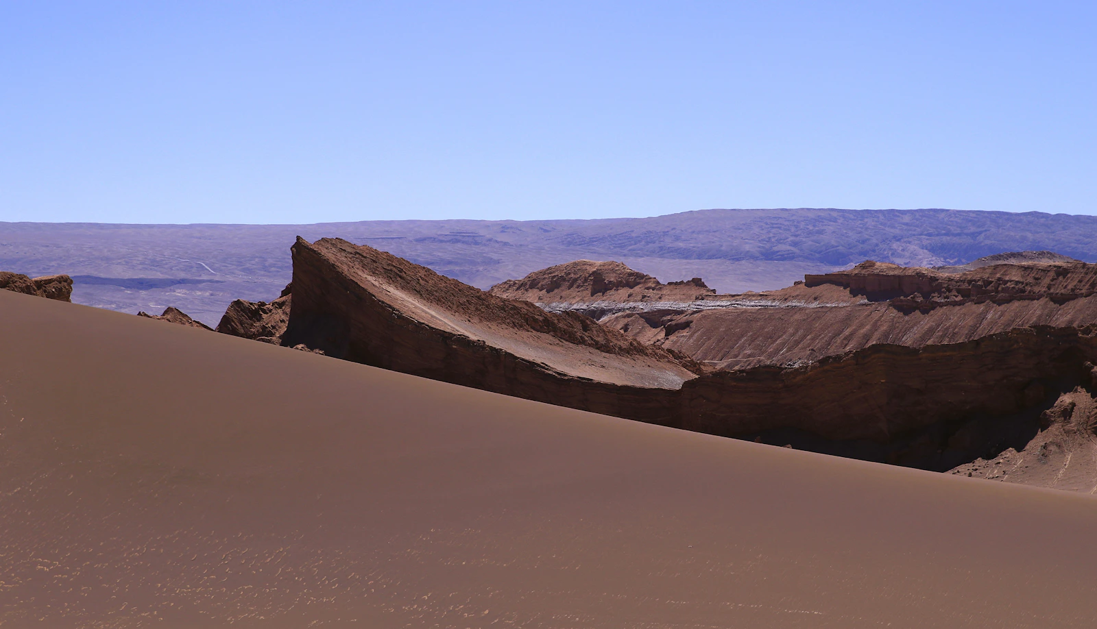 Dunas y formaciones rocosas del Valle de la Luna bajo un cielo azul