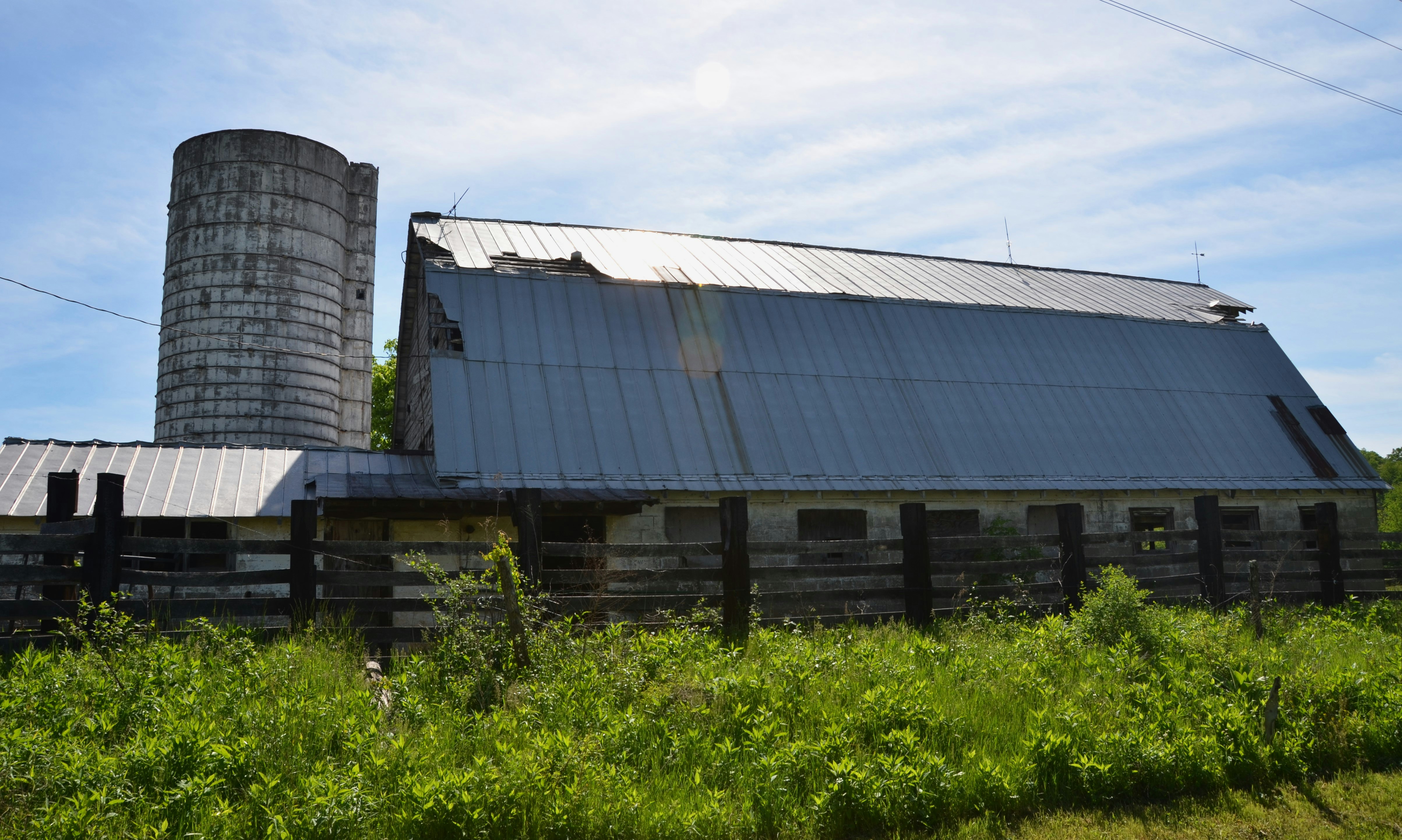 A weathered barn stands next to a silo