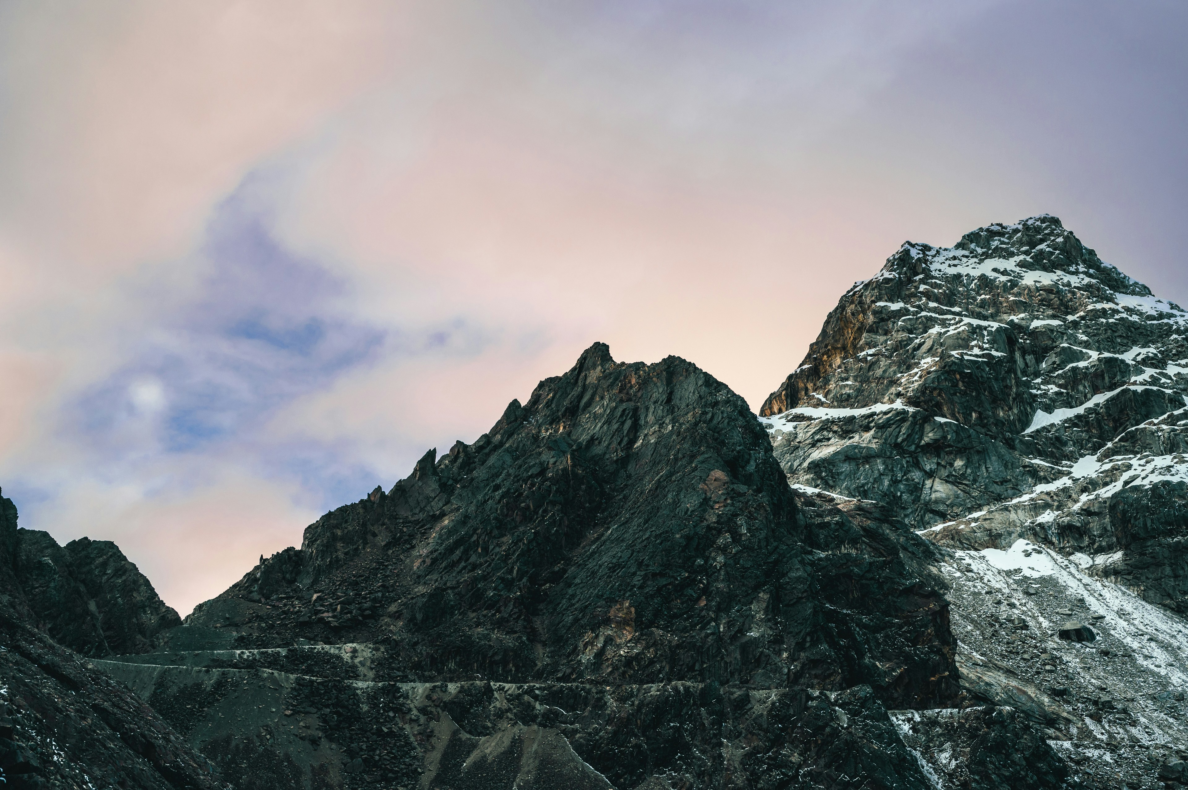Schneebedeckte Berge ragen unter einem pastellfarbenen Himmel empor.